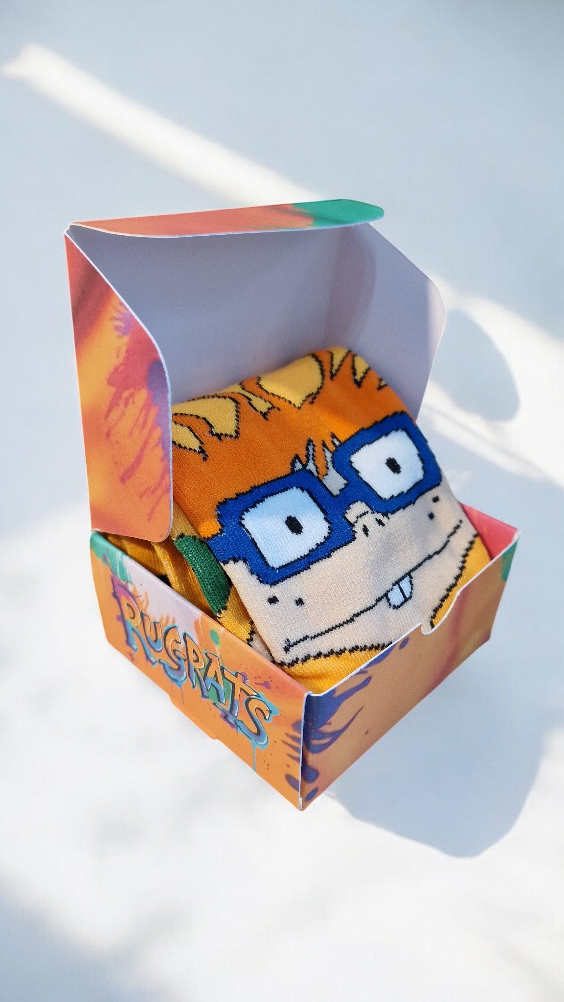 Sock with cartoon character design in a colorful packaging box on a light background