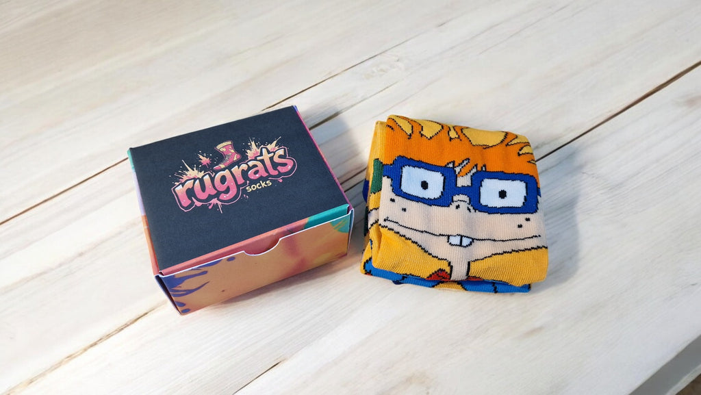 Box of 'rugrats' socks with a character-themed sock on a wooden surface