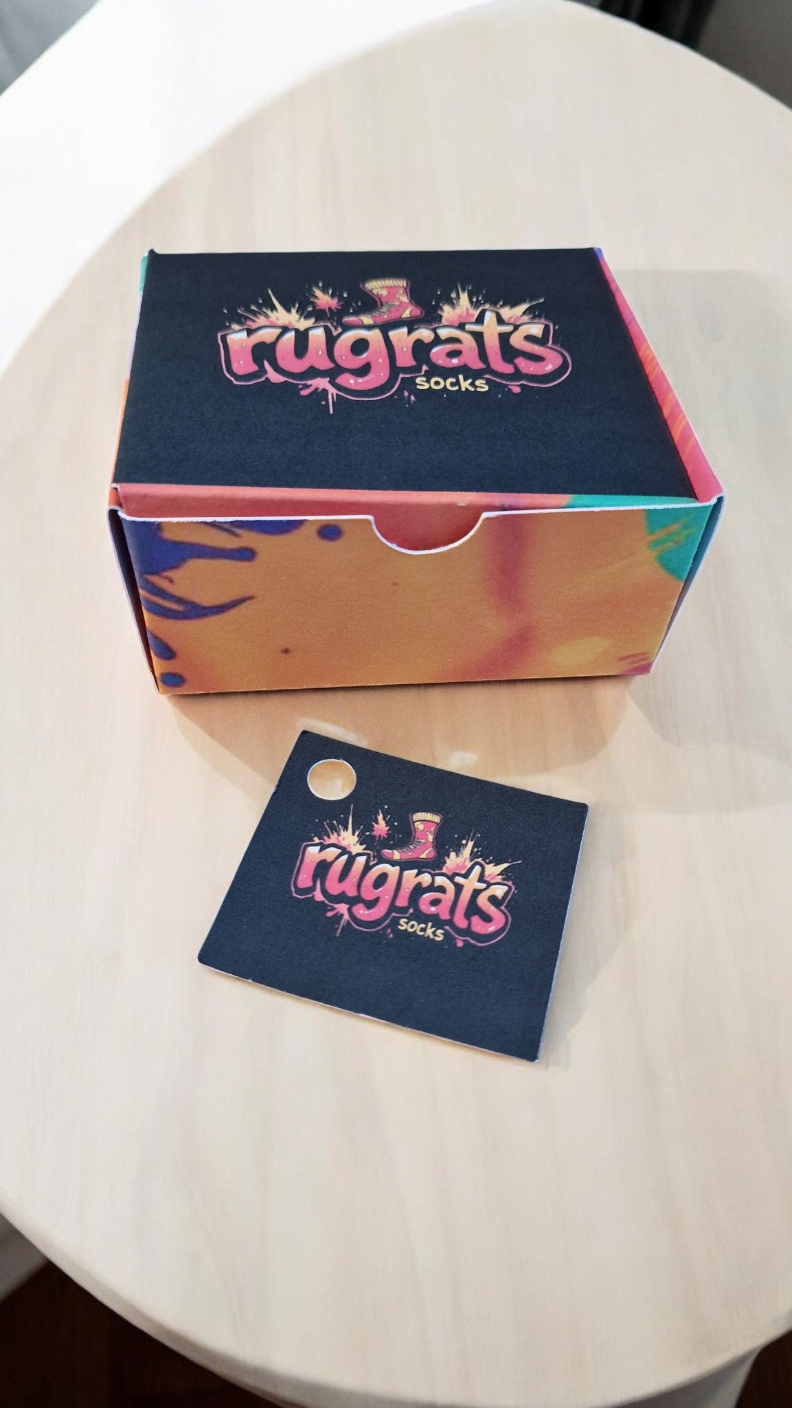Colorful box and card with 'rugrats' branding on a white surface