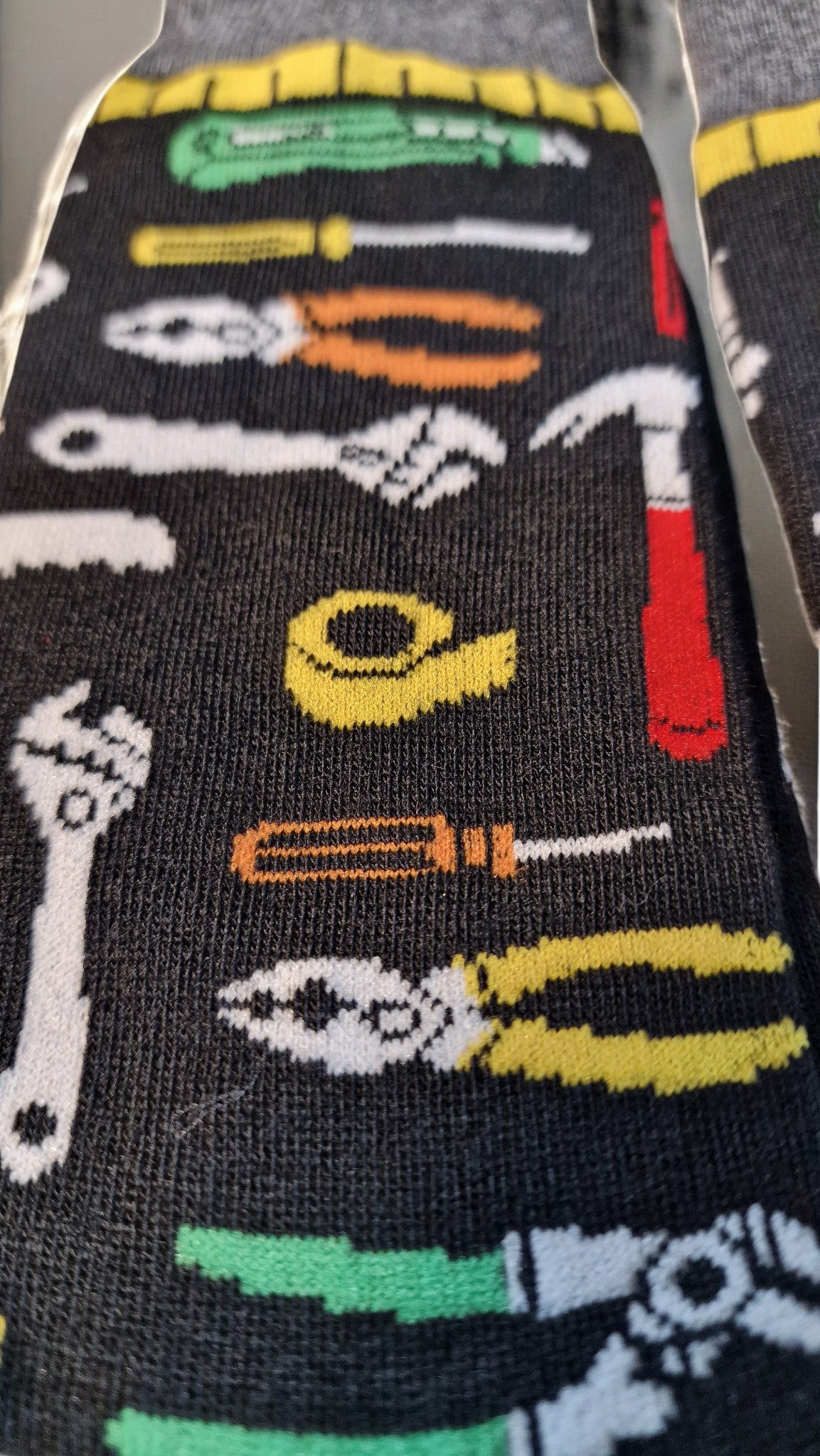 Sock with tool design featuring pliers, screwdriver, wrench, and other tools on a black background.