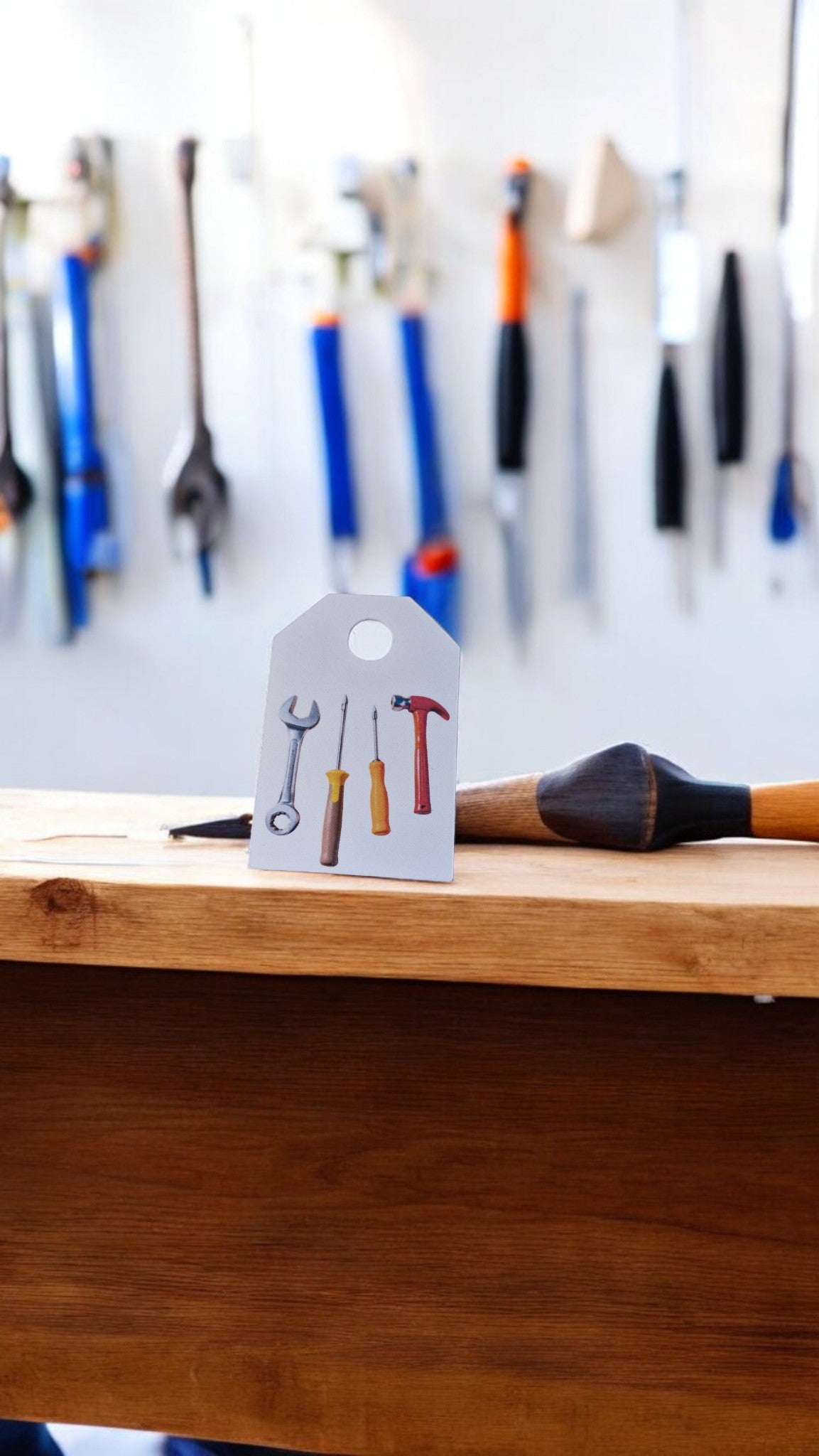 Small sign with tool illustrations on a wooden surface with tools in the background