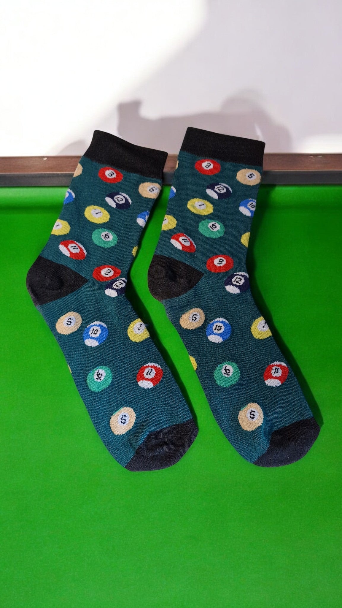 Pair of socks with pool ball design on a green surface
