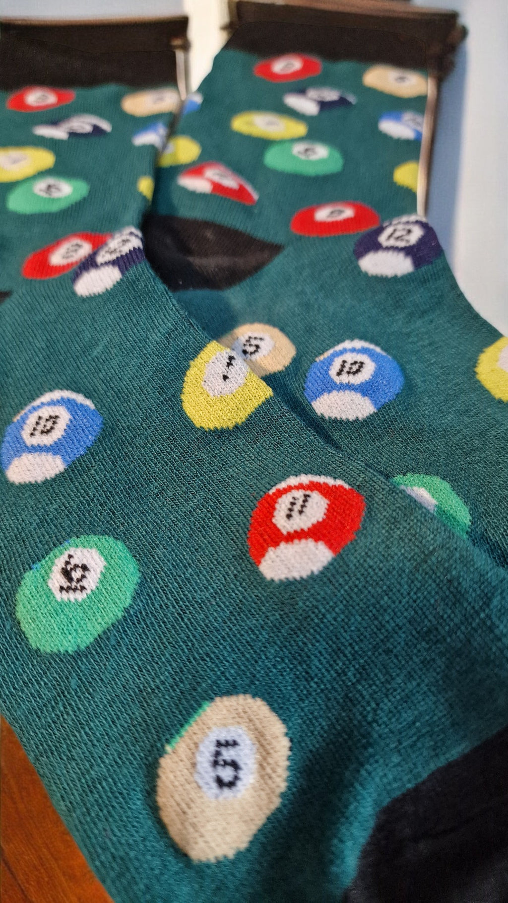 Teal socks with colorful mushroom patterns on a wooden floor.