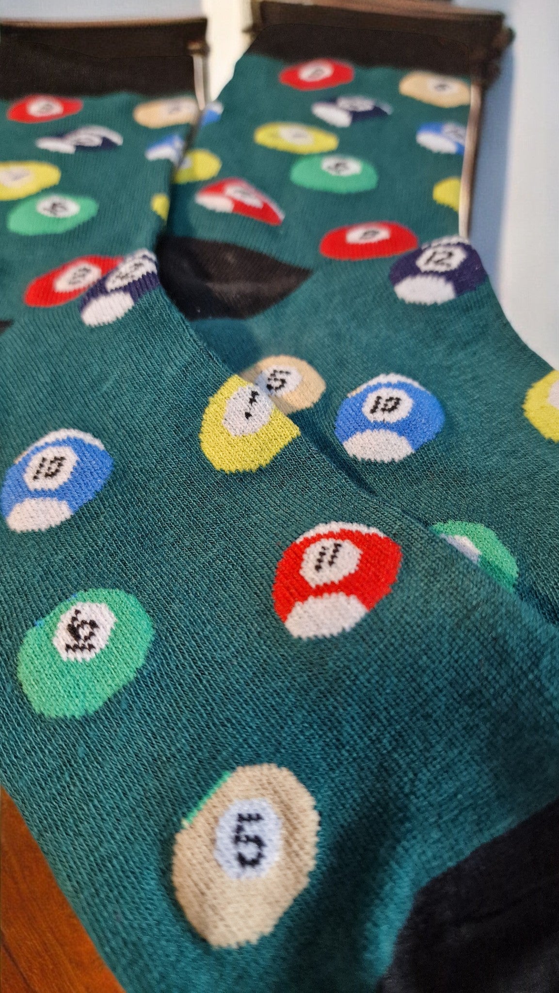 Teal socks with colorful mushroom patterns on a wooden floor.