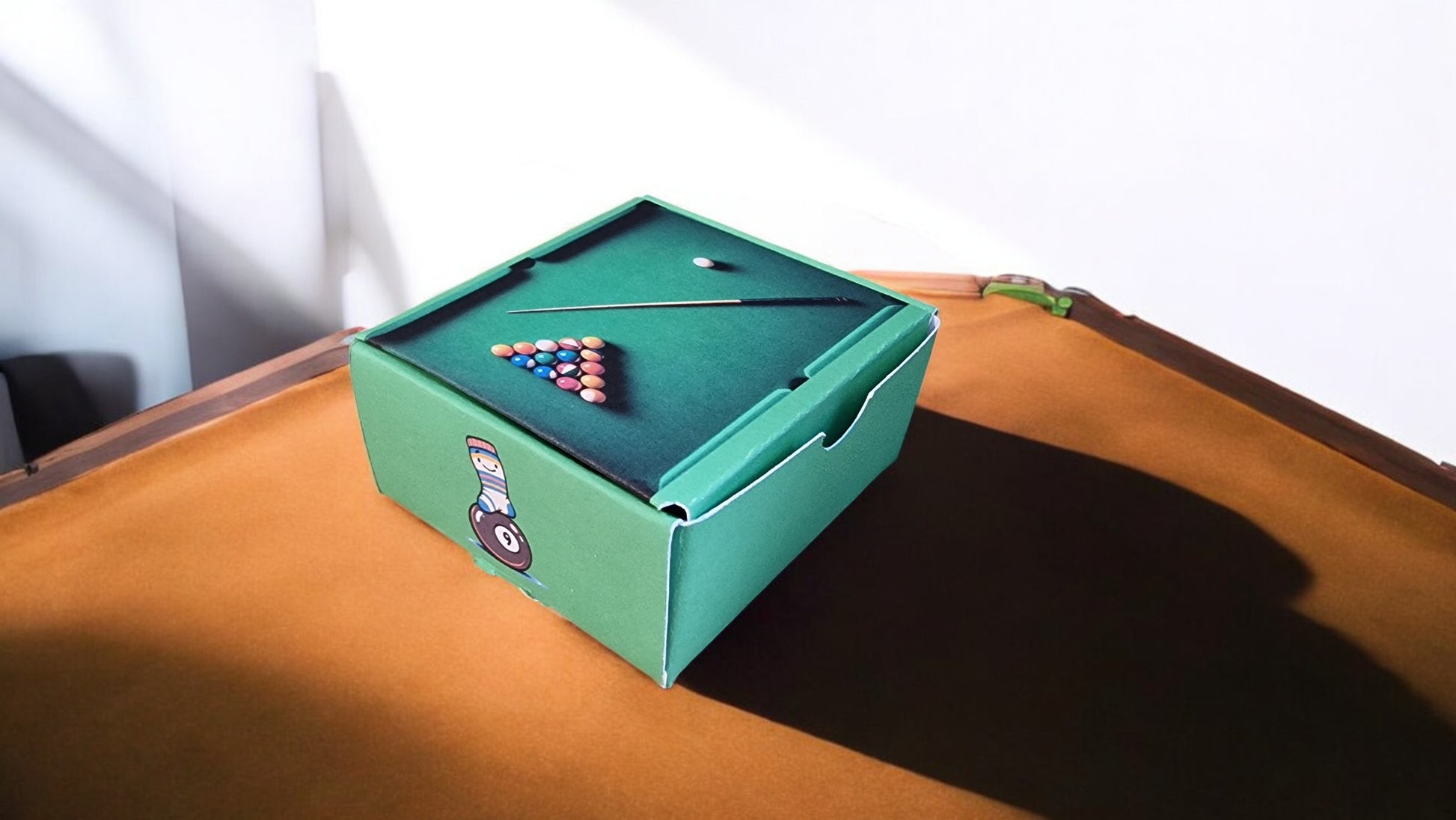 Miniature pool table with balls on a wooden surface