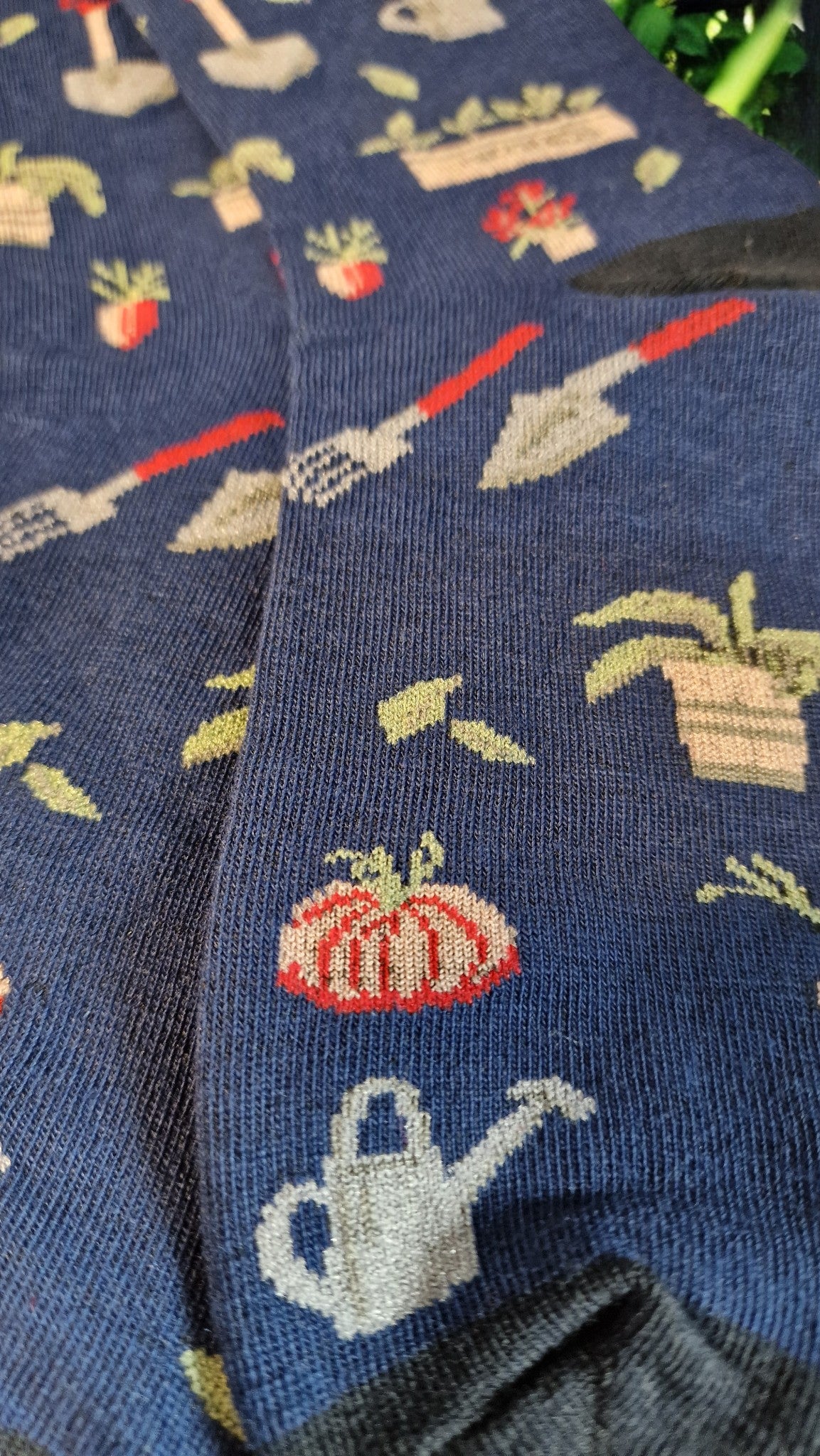 Gardening-themed socks with plants, pots, and tools on a blue background