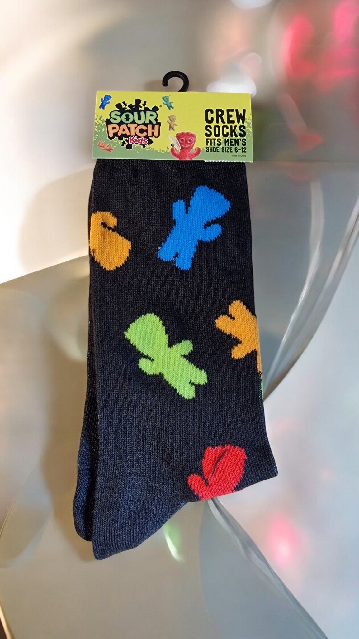Black sock with colorful character shapes on a white surface, featuring Sour Patch Kids branding.