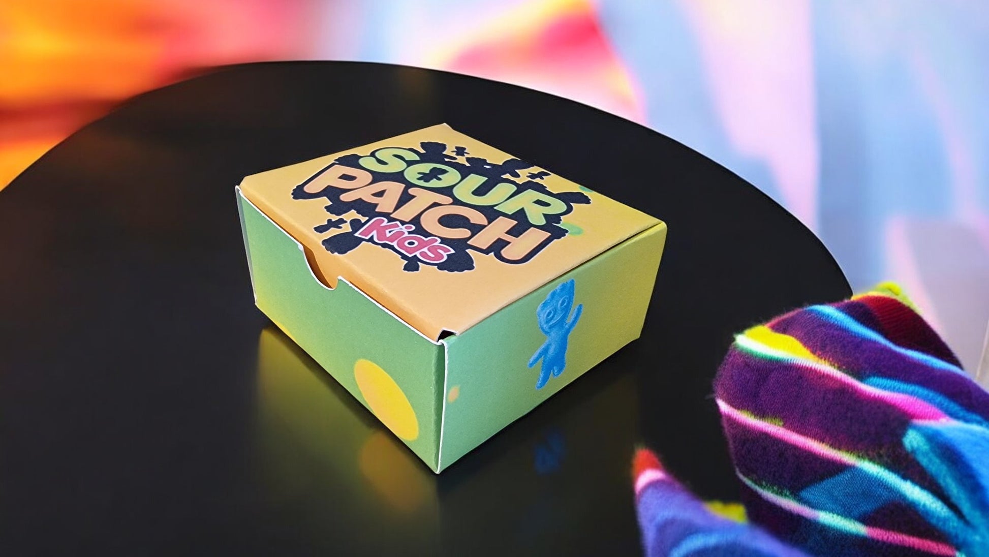Colorful sock patch box on a black surface with a colorful sock in the foreground.