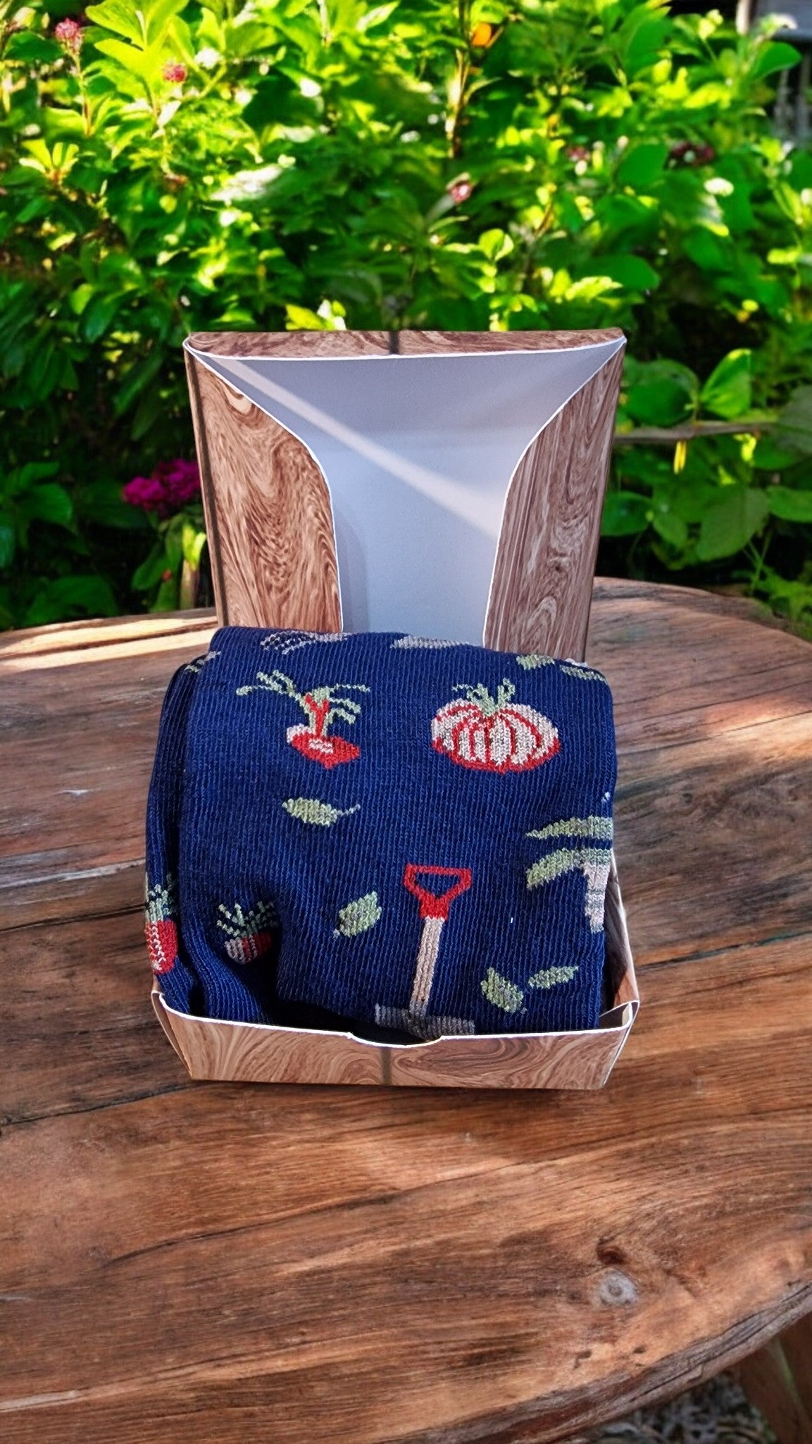 Blue embroidered towel with floral patterns in a wooden box on a wooden table outdoors.