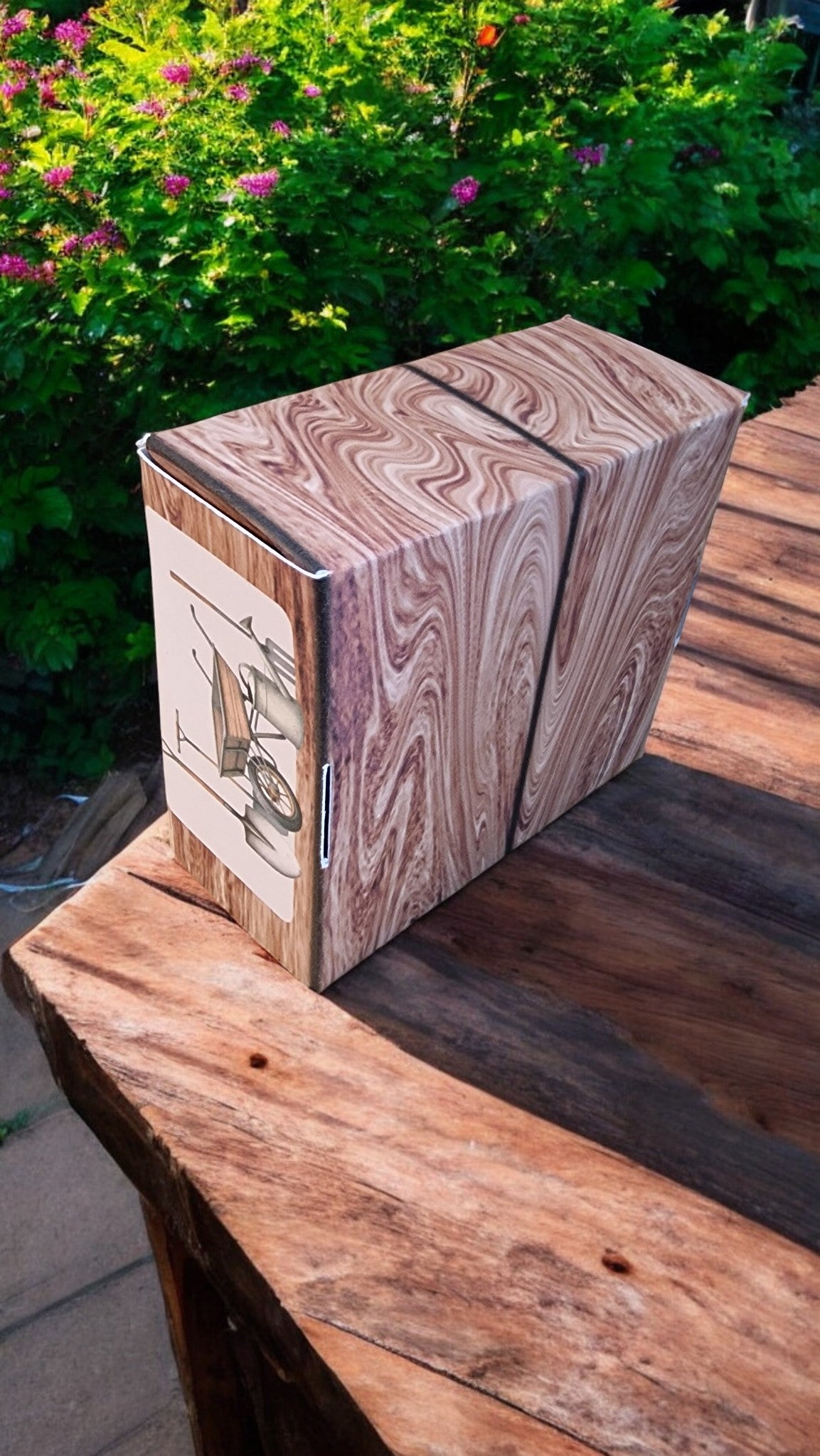 Wooden box with marbled pattern on a wooden surface with greenery in the background