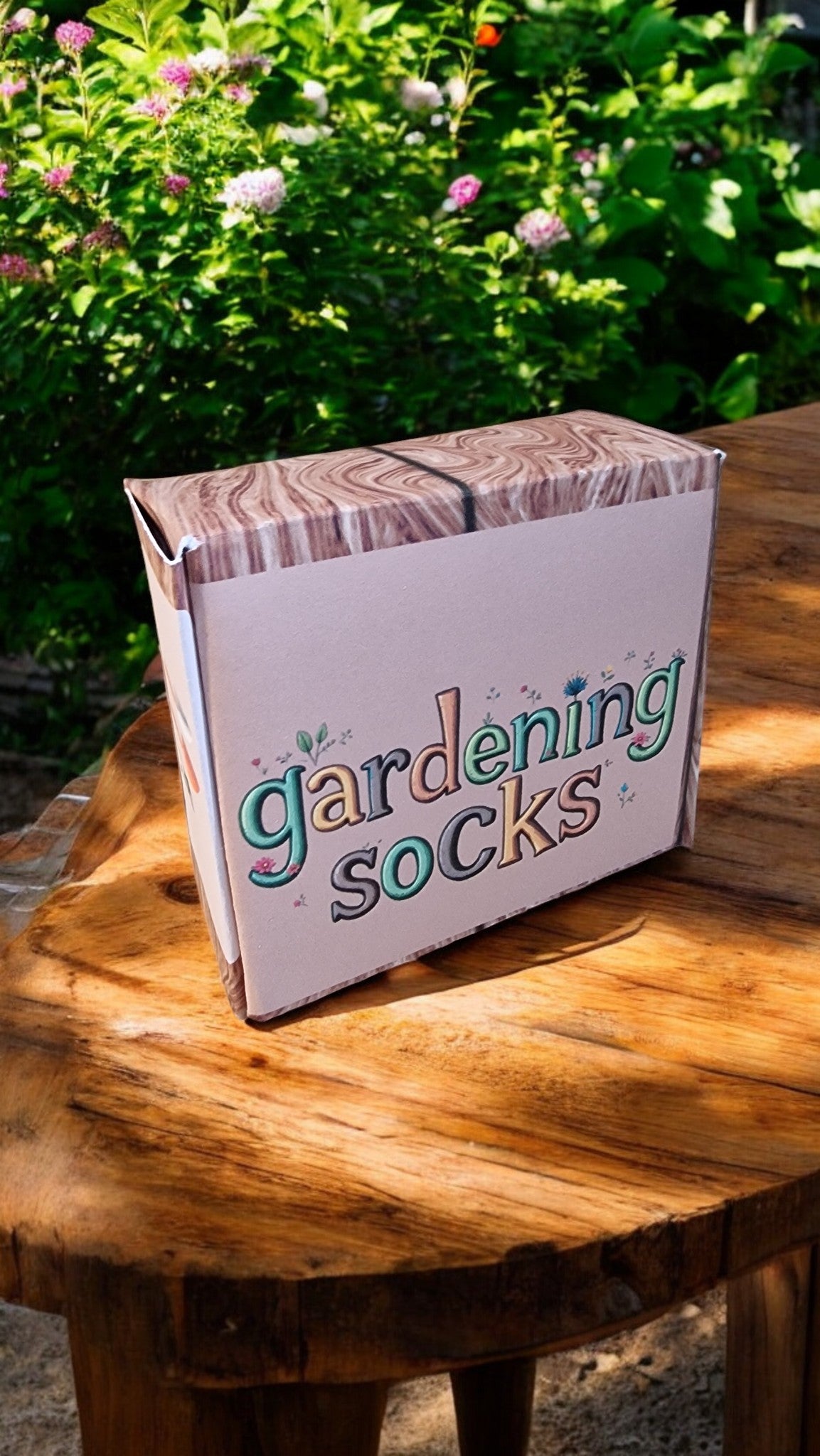 Box labeled 'gardening socks' on a wooden table with a garden background