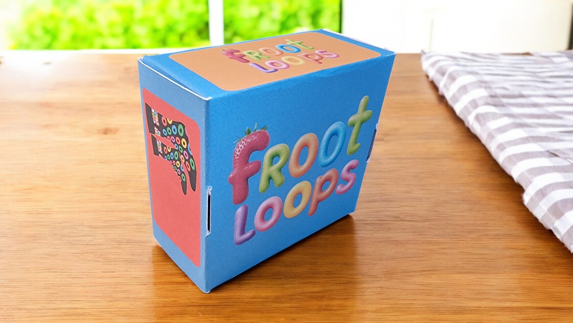 Froot Loops cereal box on a wooden table with a striped fabric in the background