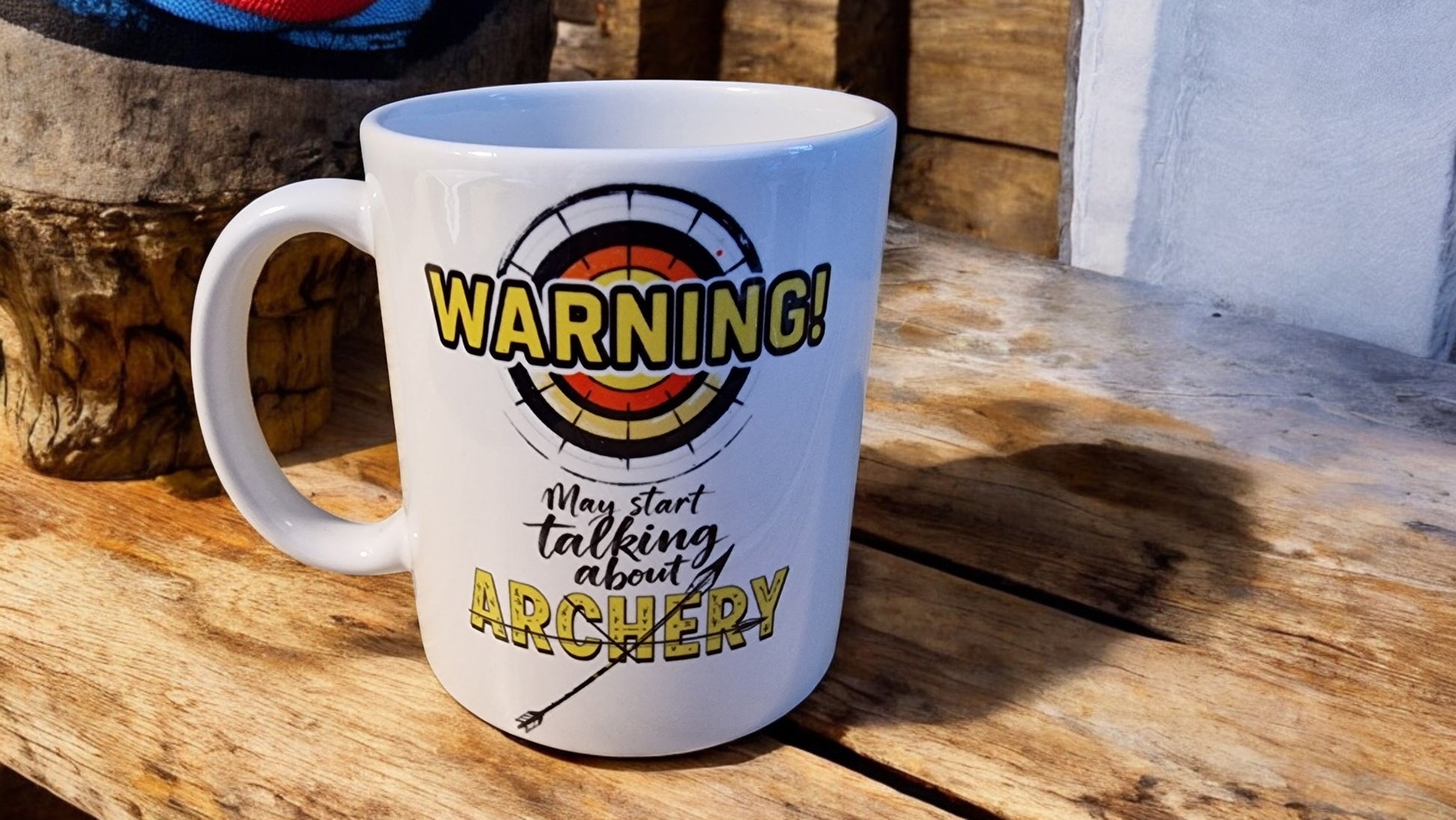 White mug with archery-themed text on a wooden surface