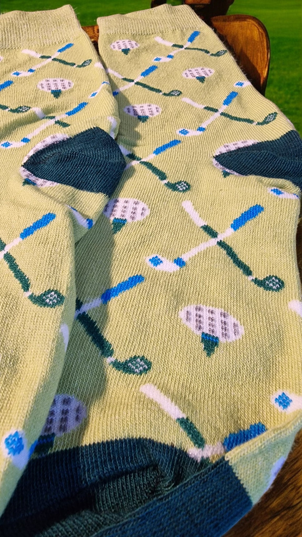 Pair of socks with golf-themed pattern on a wooden surface