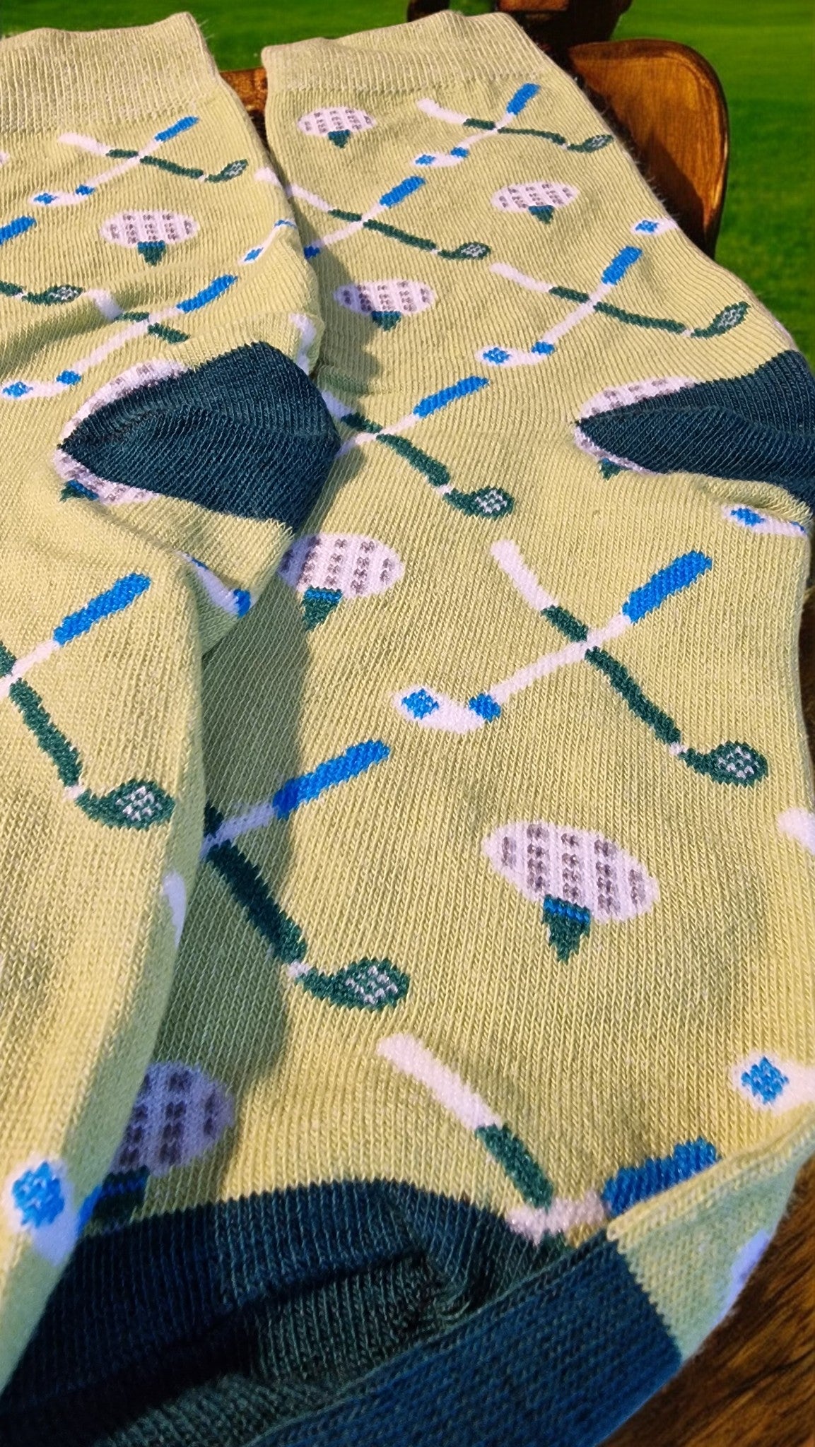 Pair of socks with golf-themed pattern on a wooden surface