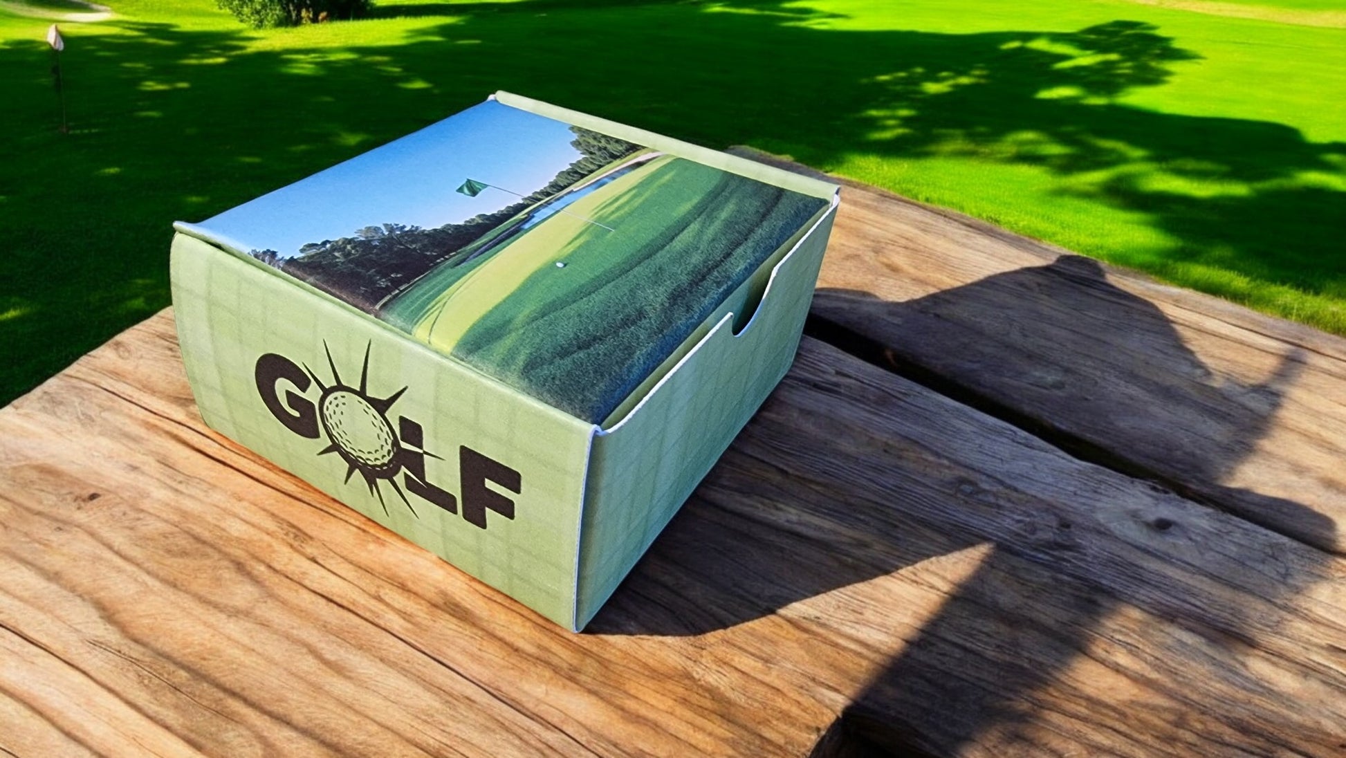 Golf-themed box on a wooden surface with a golf course in the background