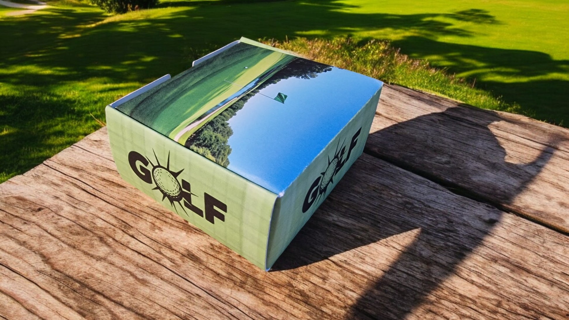 Golf-themed box on a wooden surface with grass in the background