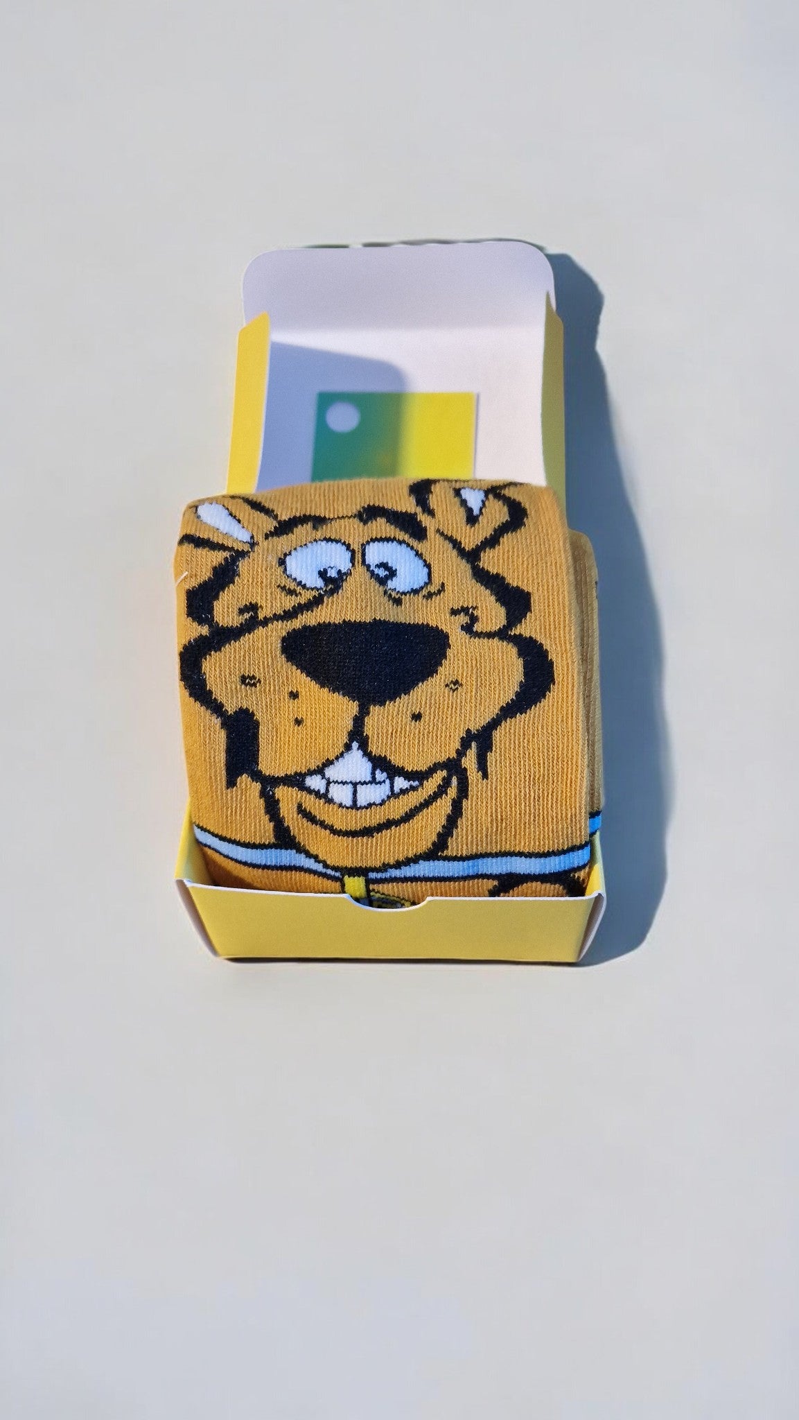 Cartoon tiger face sock in packaging on a light gray background