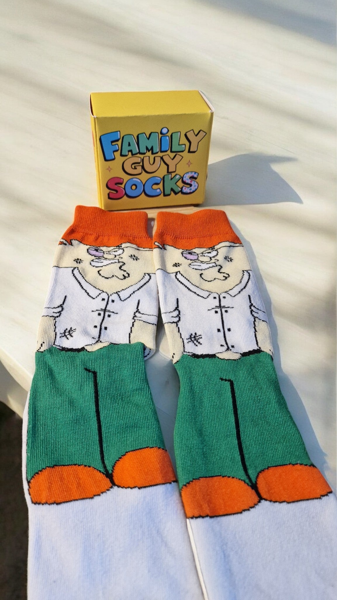 Pair of socks with cartoon character design and 'Family Guy' branded box on a light background
