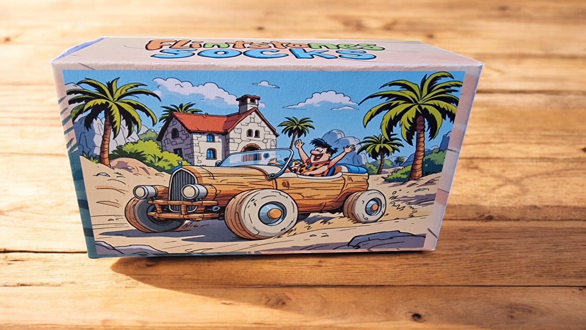 Box of socks with a beach scene design featuring a car and palm trees on a wooden surface.