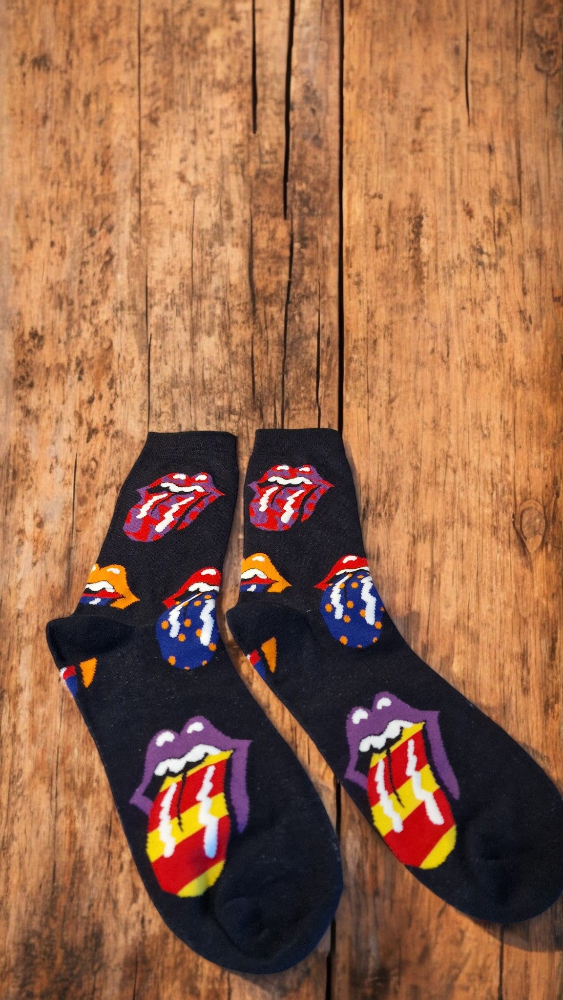 Black socks with colorful Rolling Stones logo on a wooden surface