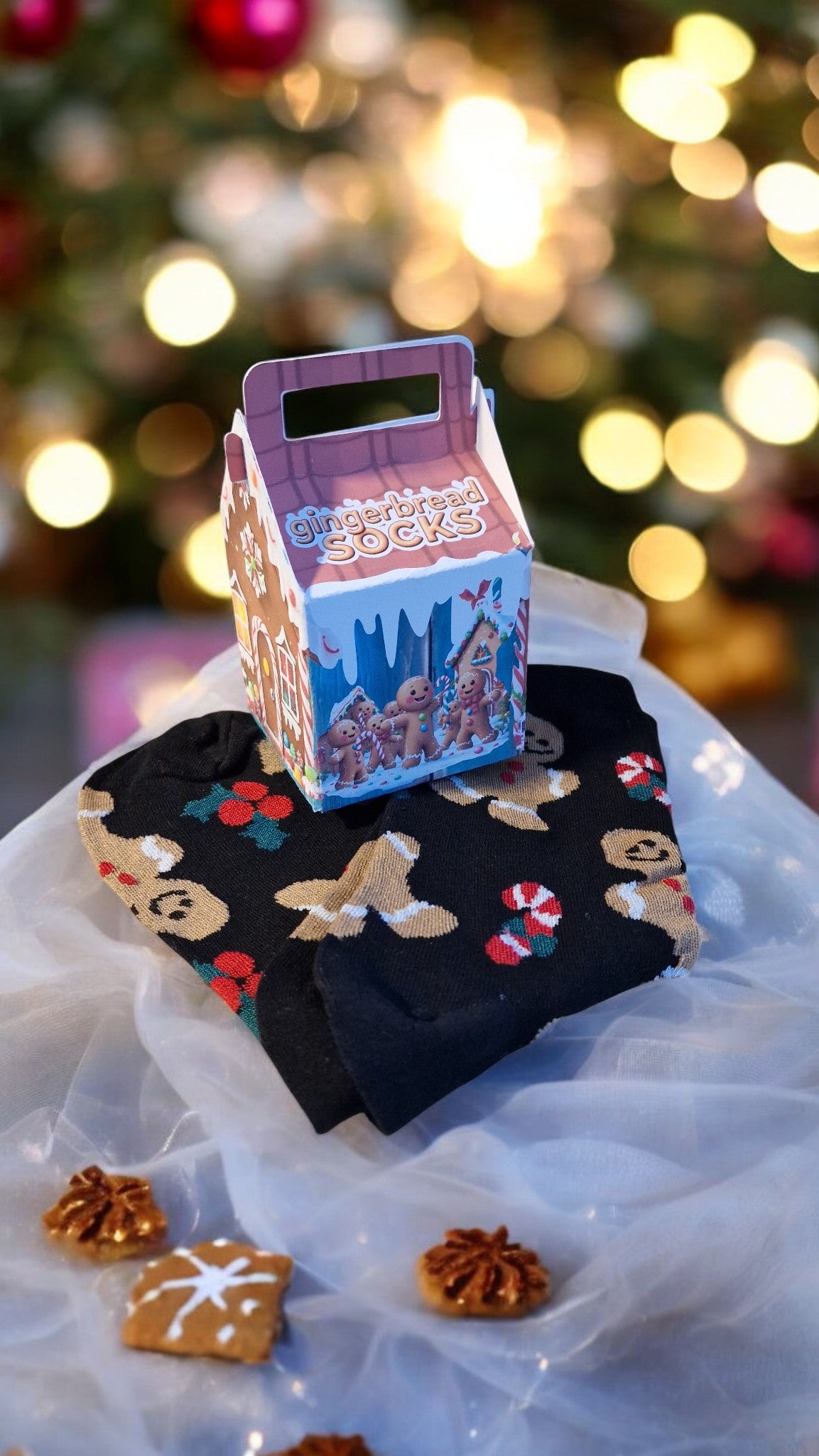 Decorative box with gingerbread men design on a white surface with a blurred Christmas tree in the background.