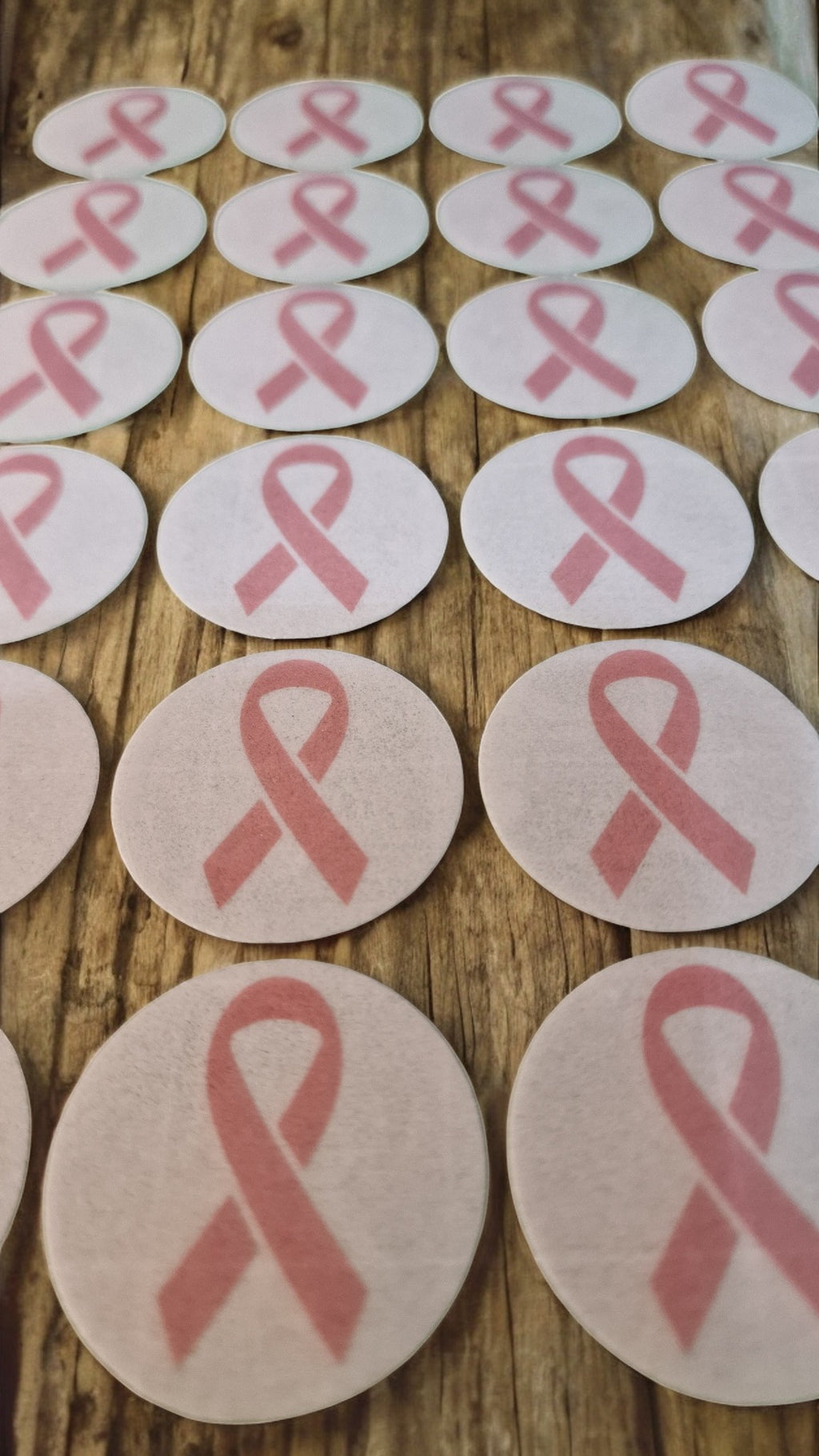 Pink breast cancer awareness ribbons on round white cards arranged on a wooden surface.