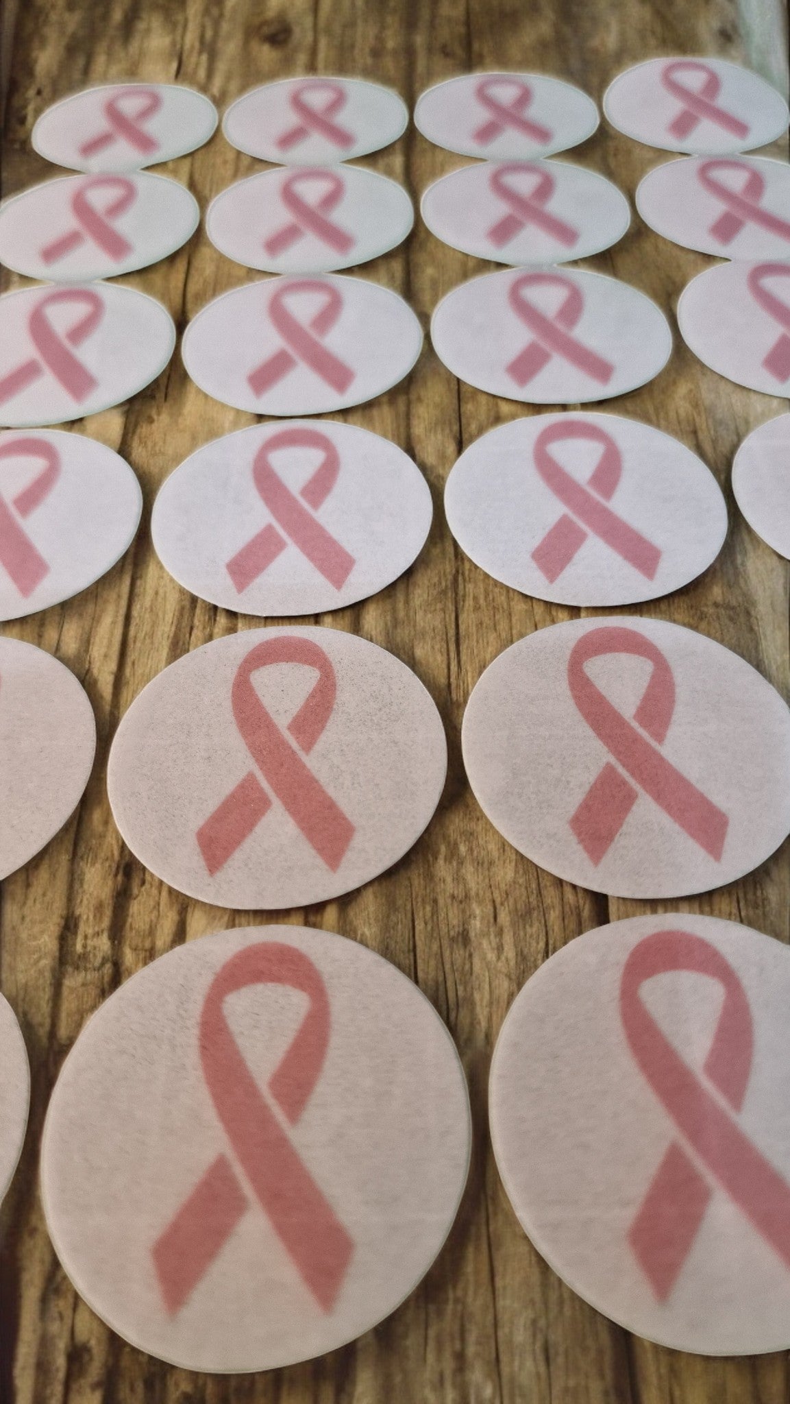 Pink breast cancer awareness ribbons on round white cards arranged on a wooden surface.