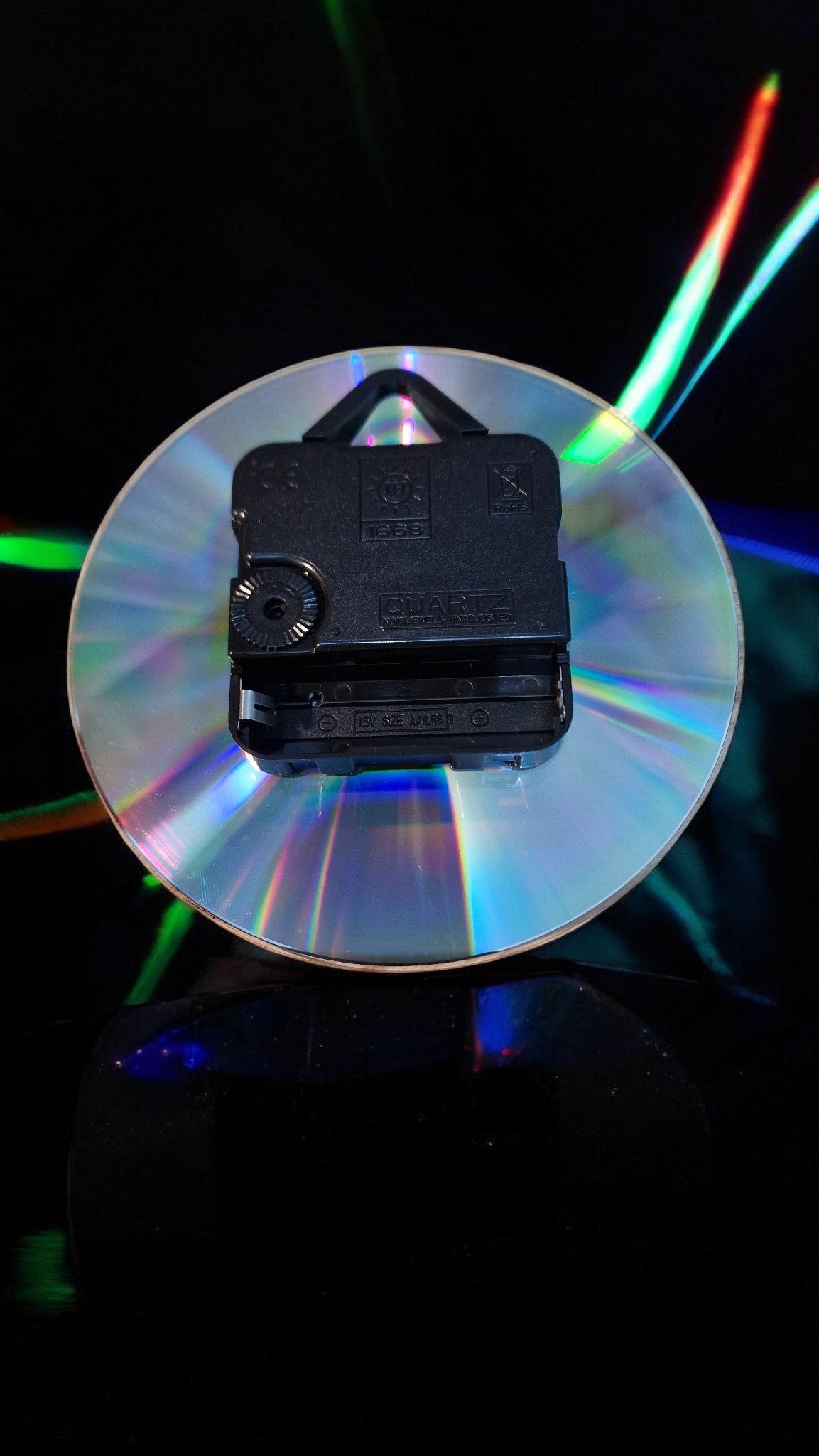 Black electronic device on a reflective surface with colorful lights in the background