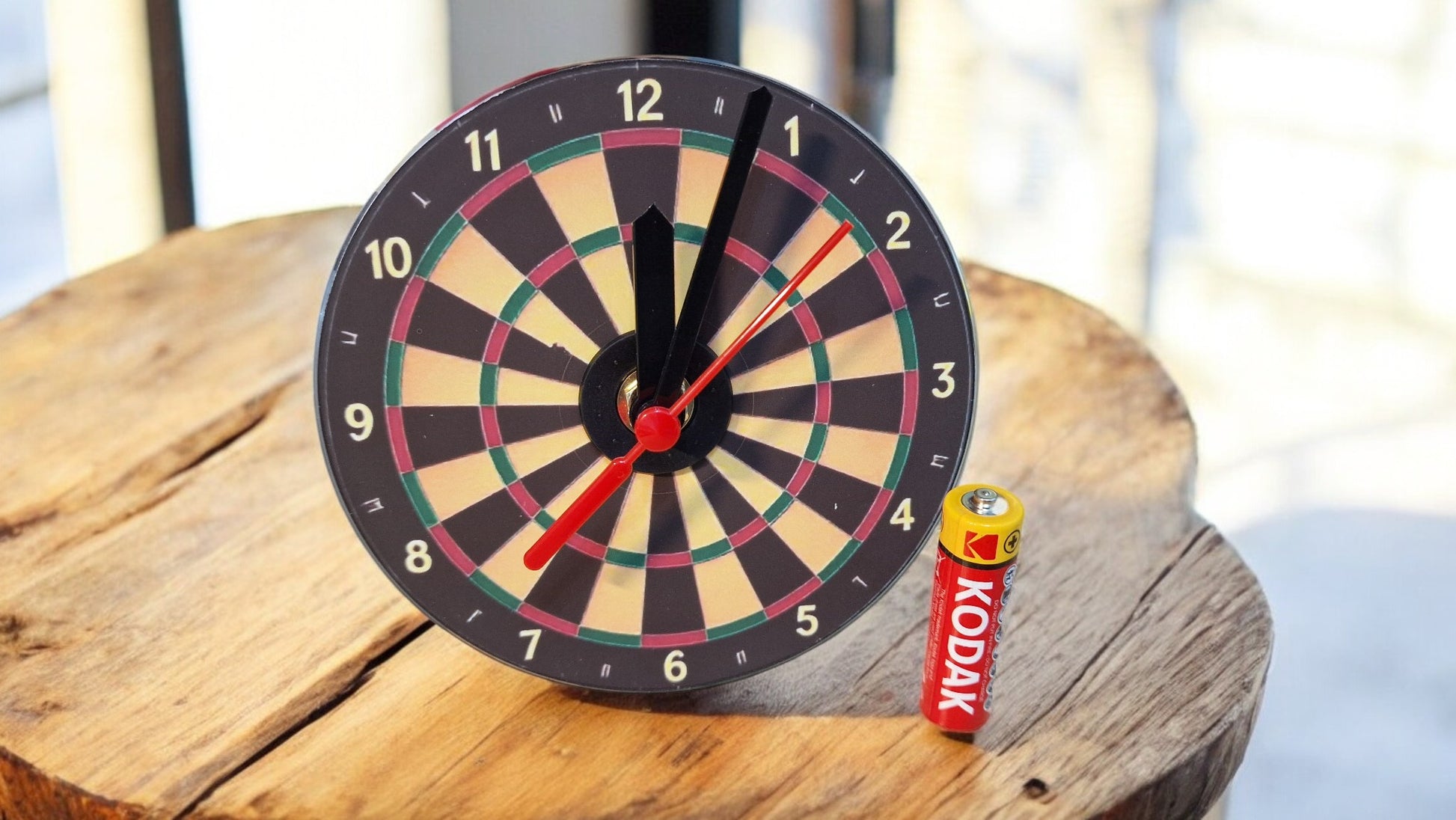 Dartboard clock on a wooden surface with a Kodak box in the background