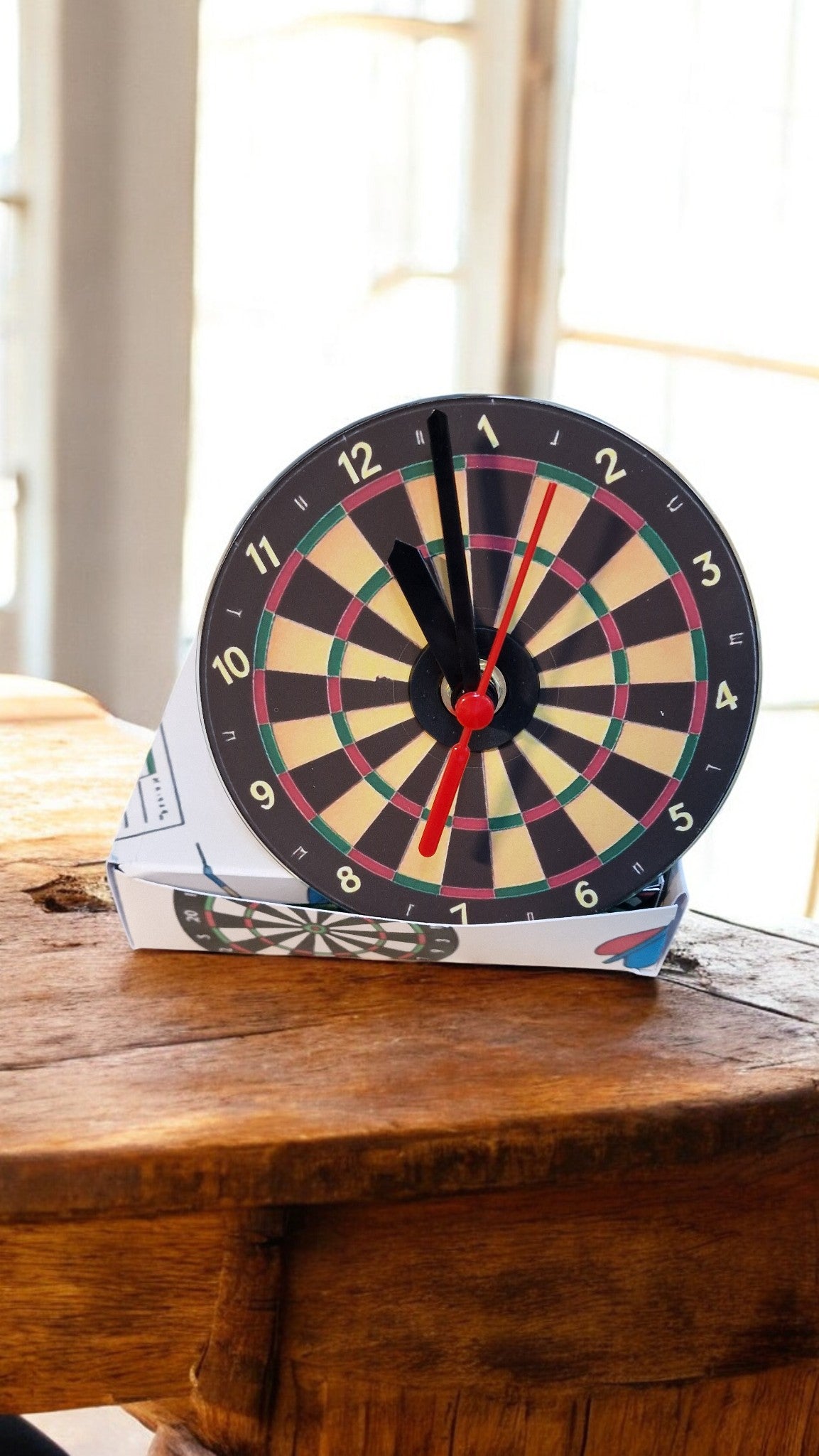 Dartboard clock on a wooden surface with a window in the background