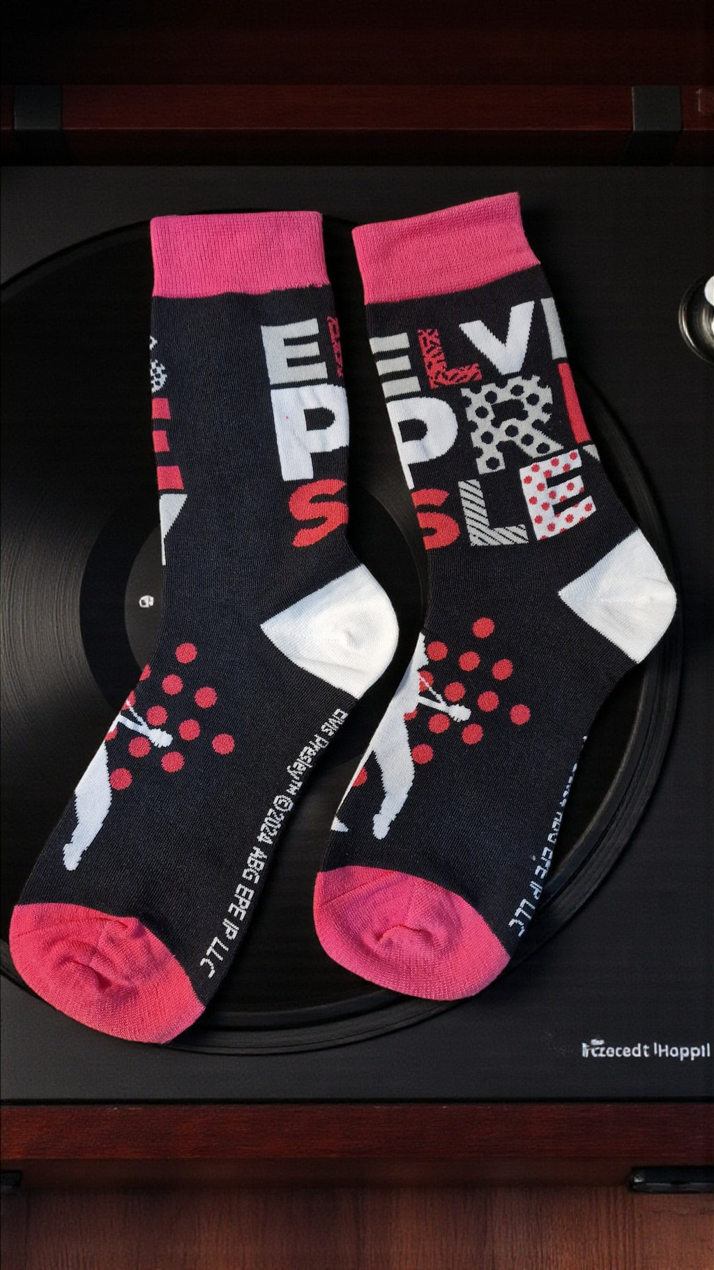 Two socks with red and pink accents on a black surface