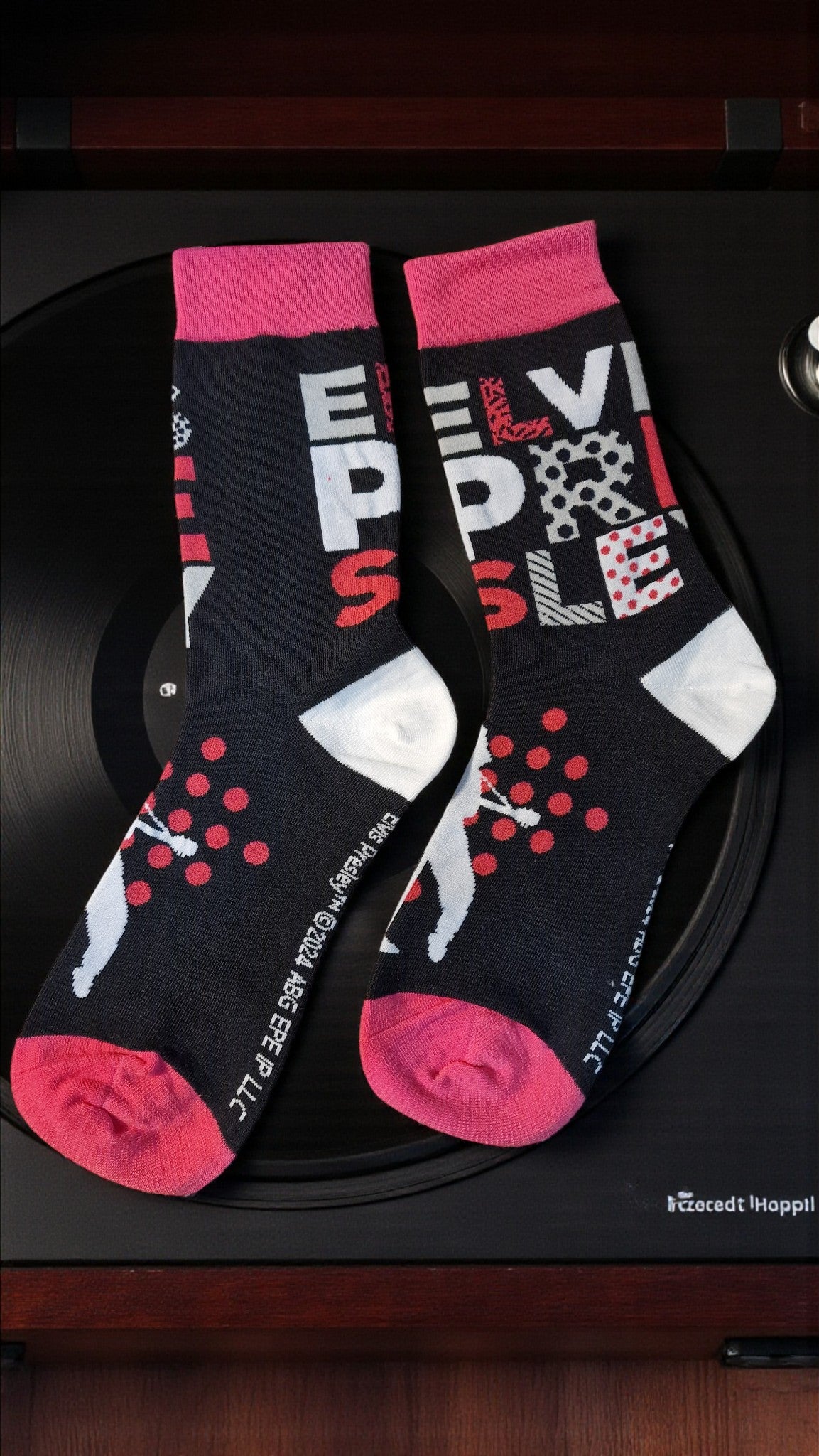 Two socks with red and pink accents on a black surface