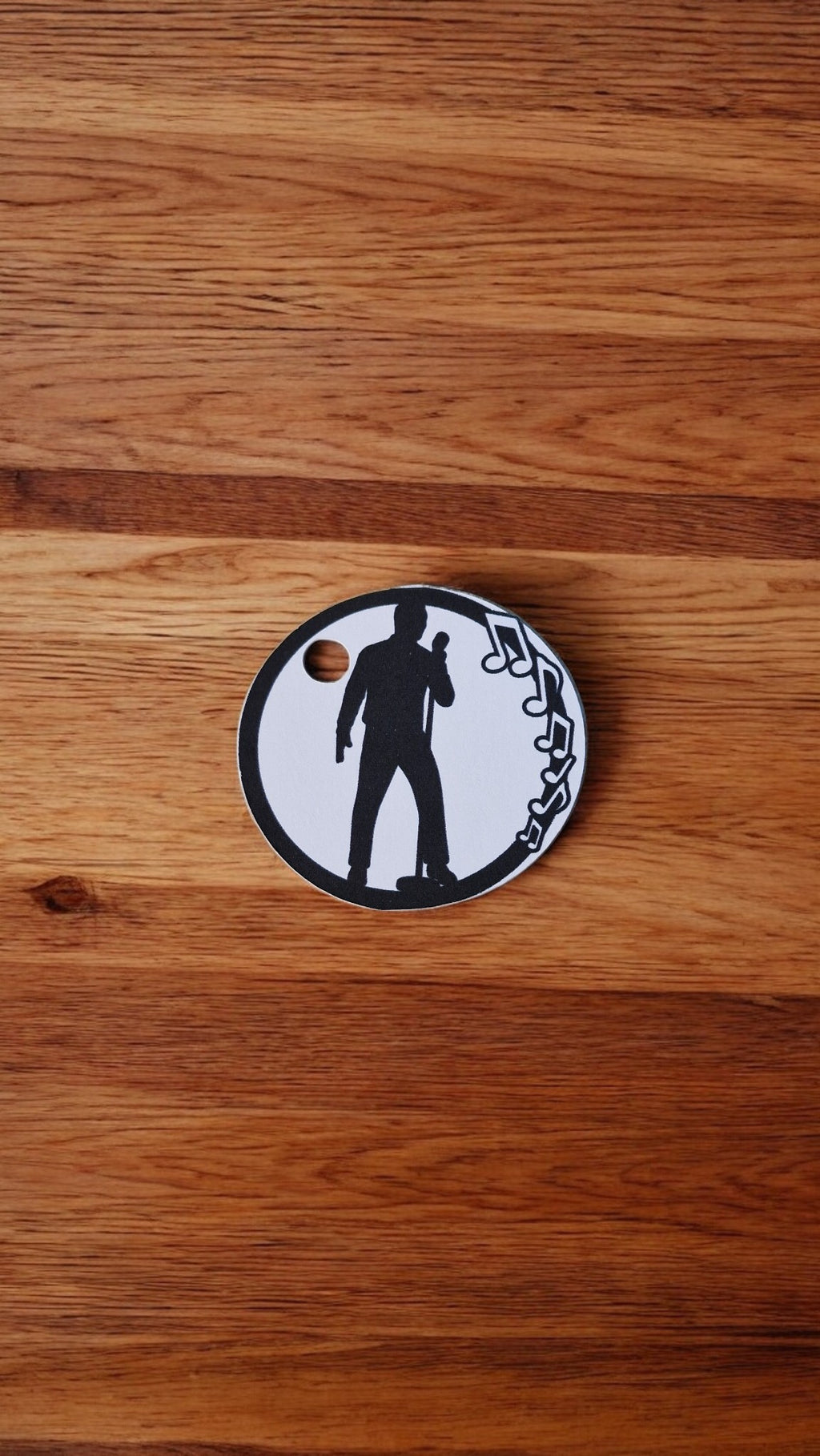 Circular metal badge with a black silhouette design on a wooden surface