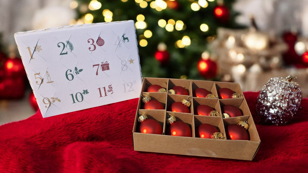 Advent calendar with red ornaments on a red surface with blurred Christmas tree in the background