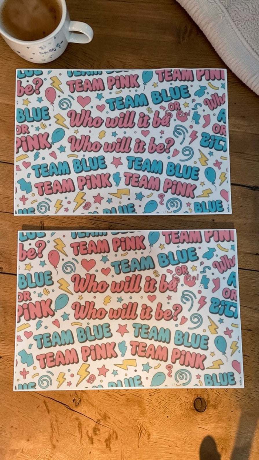 Two sheets of paper with 'Team Pink' and 'Team Blue' text on a wooden surface.