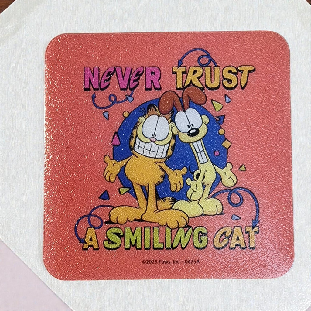 Coaster with cartoon characters and text 'Never Trust a Smiling Cat' on a red background