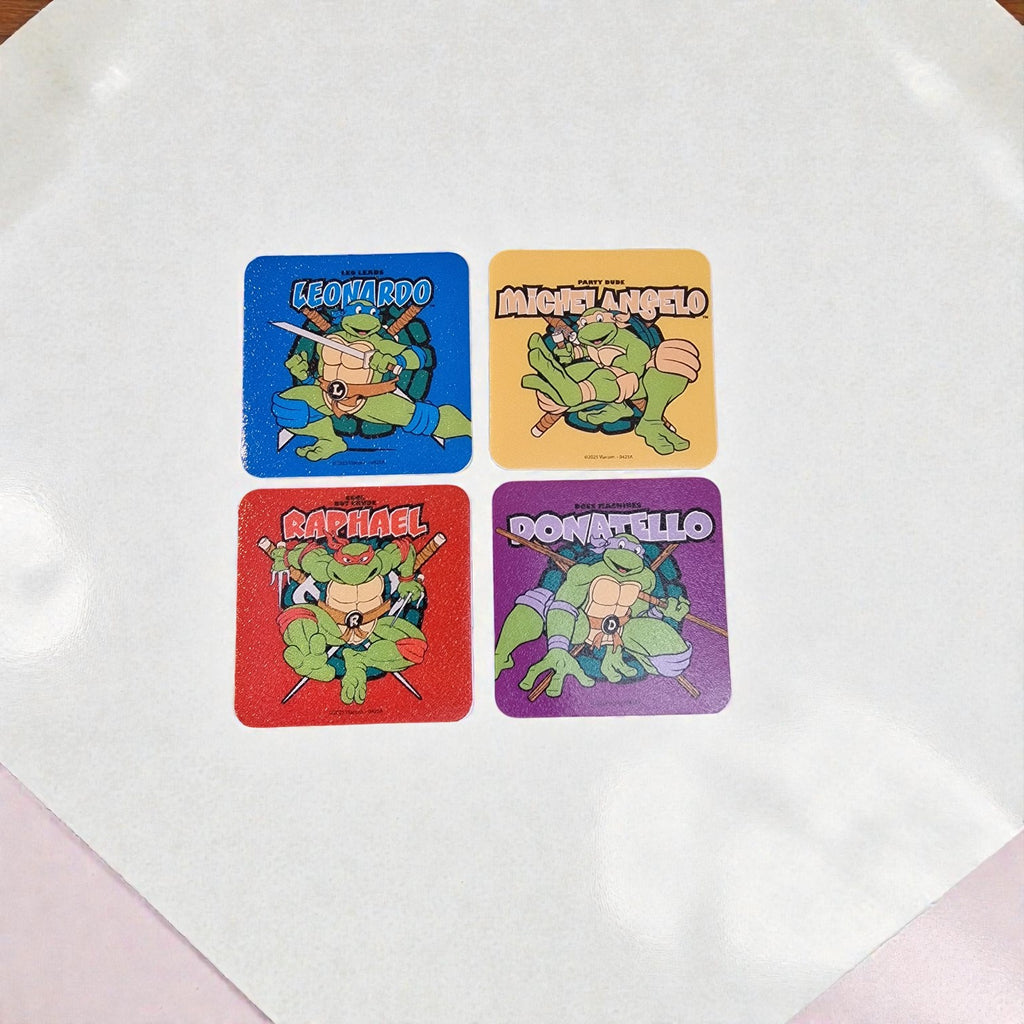 Four cartoon turtle stickers labeled Leonardo, Michelangelo, Raphael, and Donatello on a white surface.