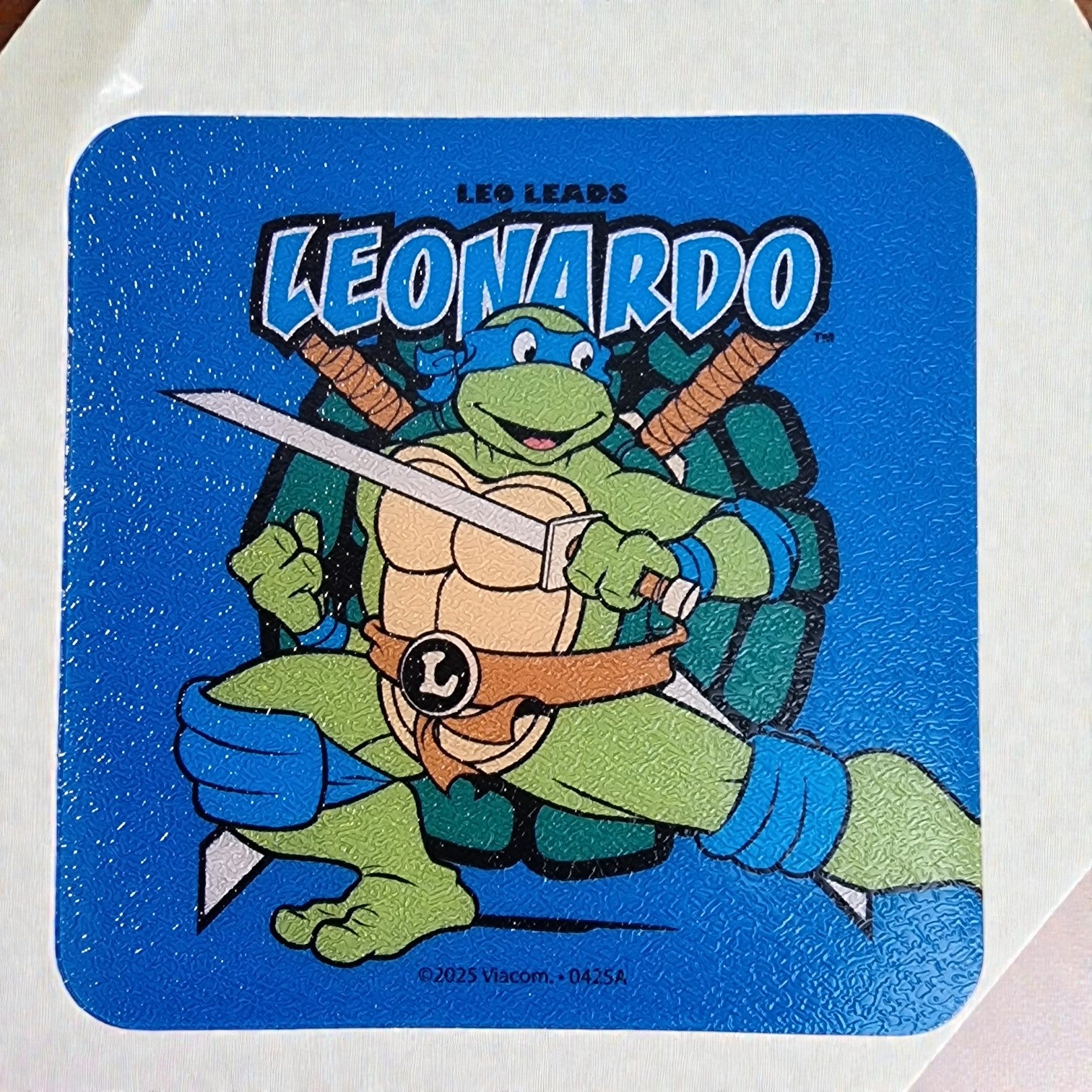 Sticker of a cartoon turtle character holding swords with 'LEO LEADS LEONARDO' text on a blue background.