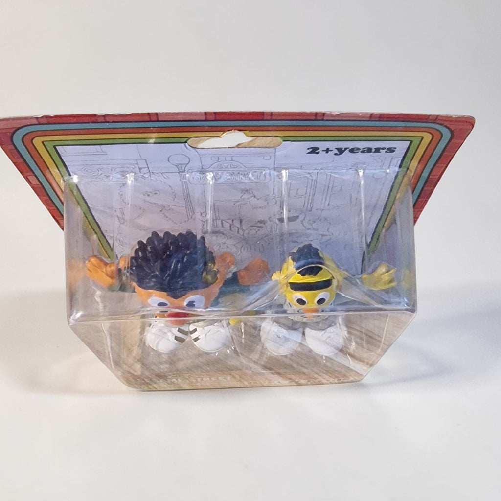 Two small figurines in a clear packaging with a colorful label on a white background