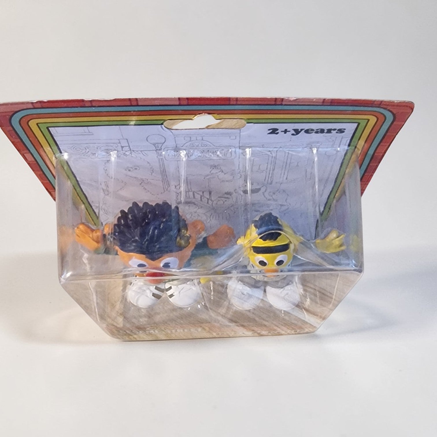 Two small figurines in a clear packaging with a colorful label on a white background