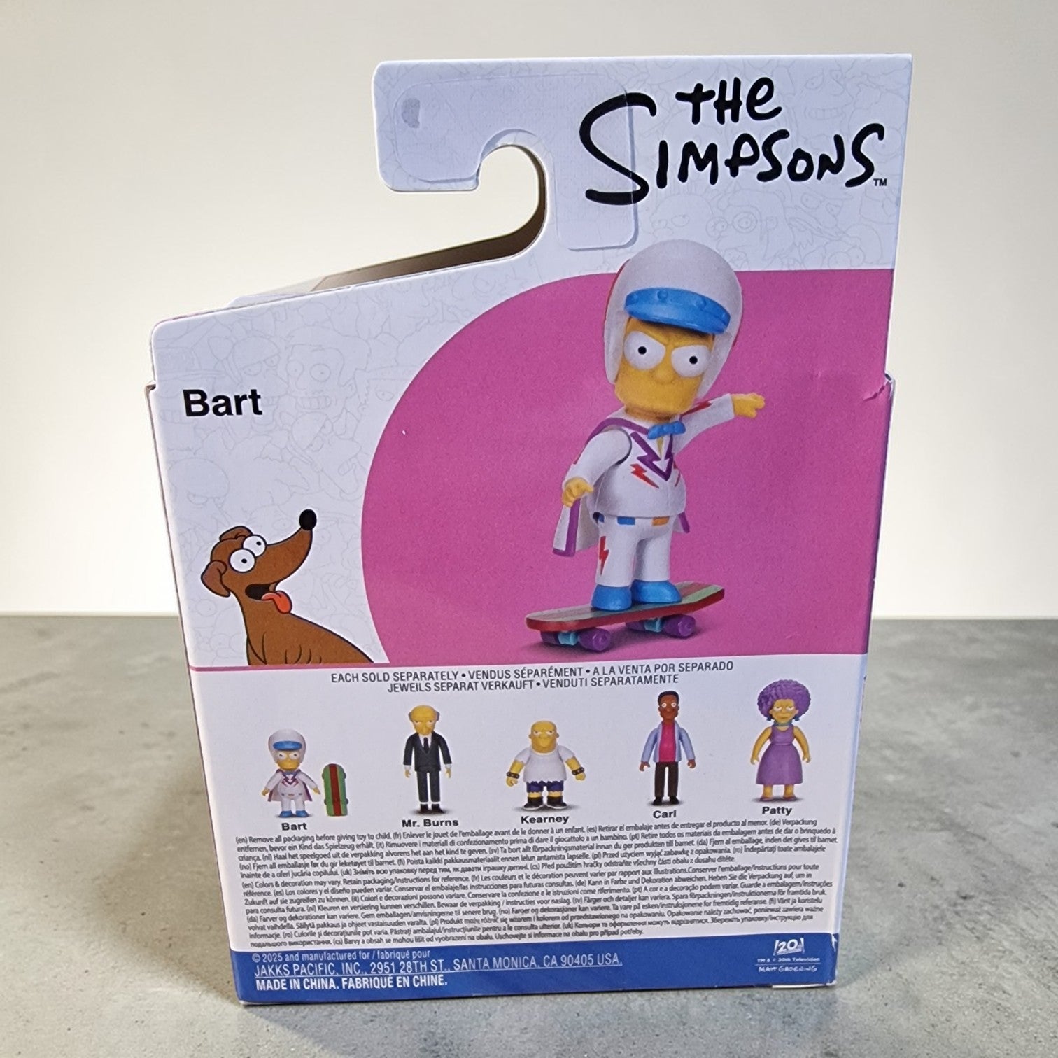 Package of a 'The Simpsons' Bart Simpson action figure with a pink circle on a gray surface.