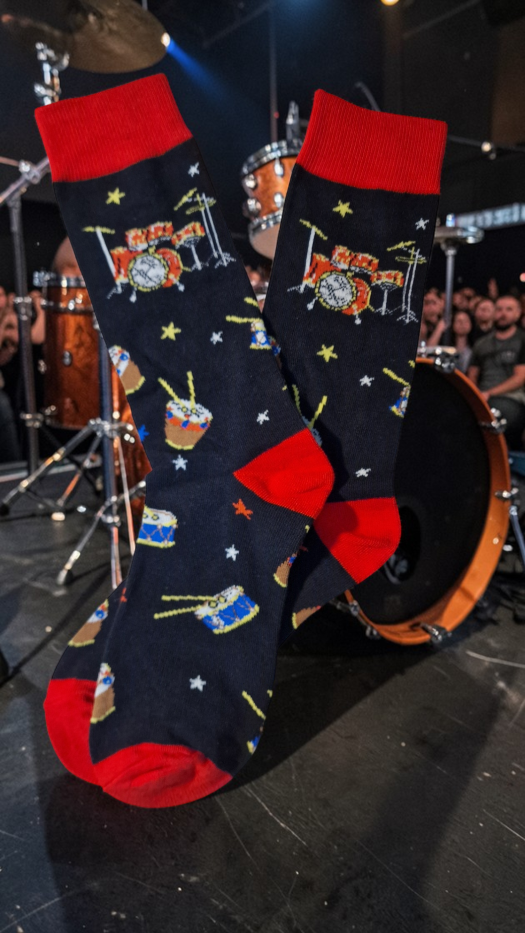 Pair of socks with musical instrument design held up against a drum set background