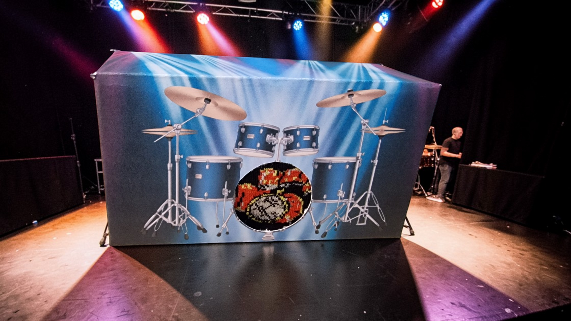 Stage with drum set backdrop and person playing drums