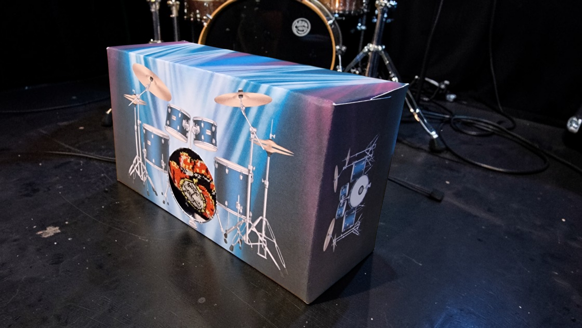 Coffin-shaped box with drum set design on a stage