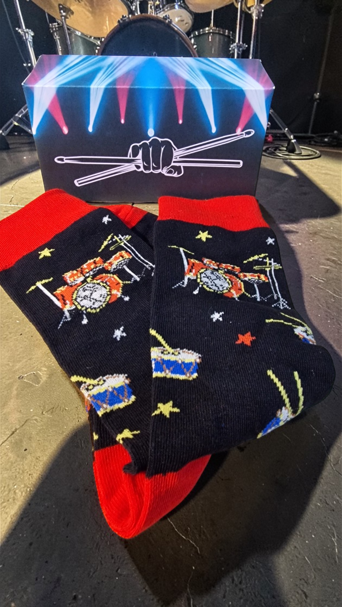 Pair of socks with musical instrument designs on a box labeled 'Drum Kit'.