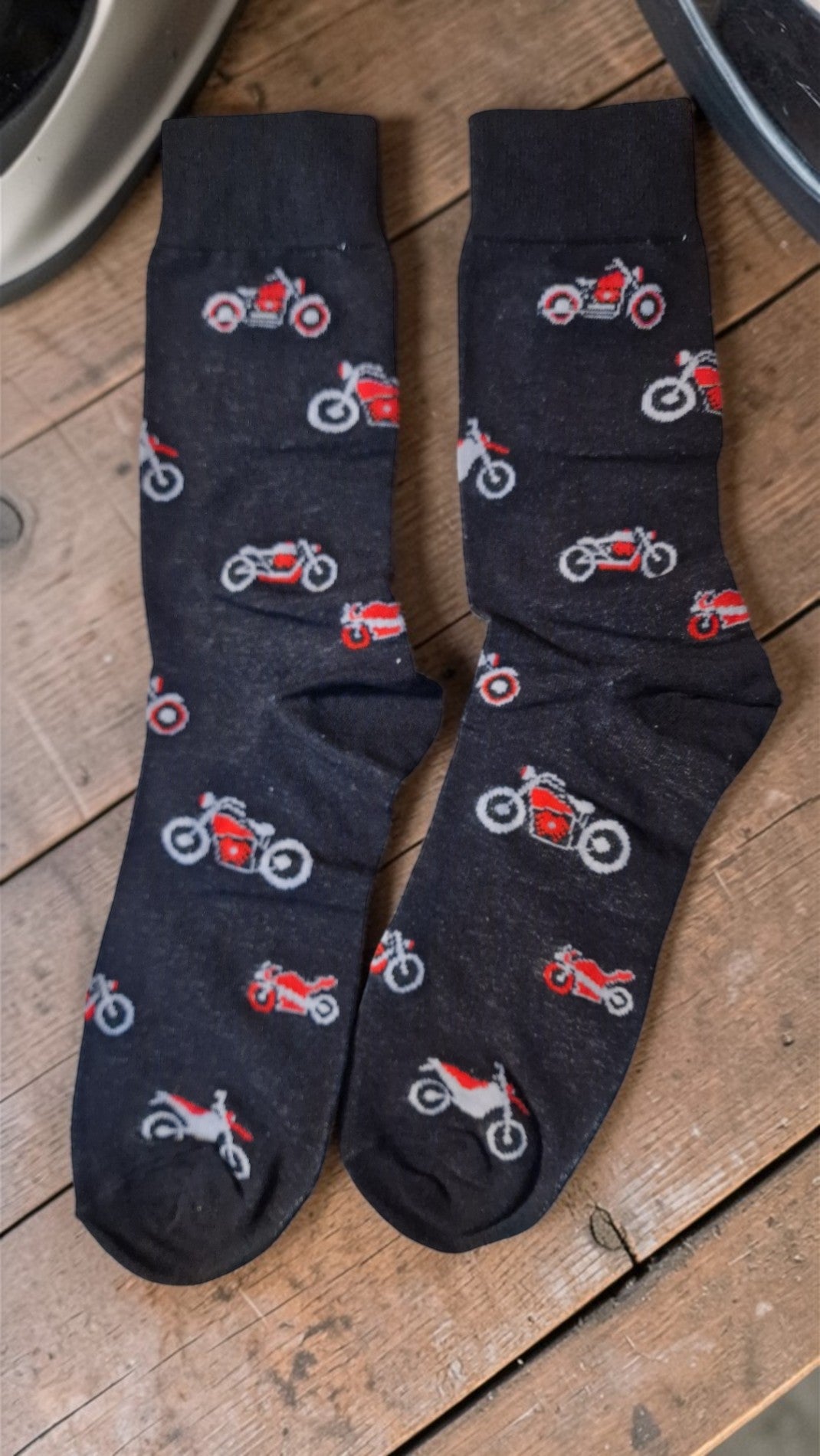 Pair of dark blue socks with motorcycle patterns on a wooden surface