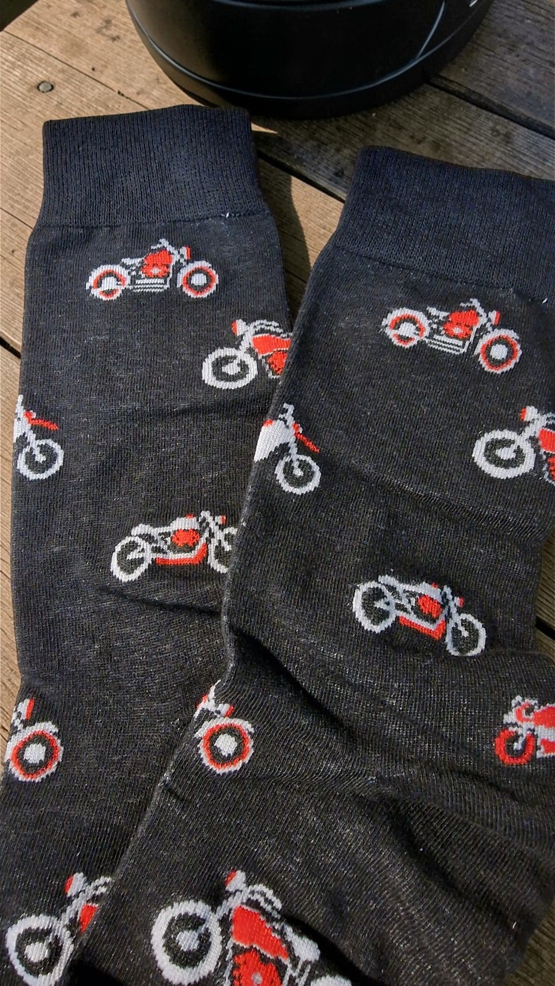 Dark gray socks with red and white motorcycle patterns on a wooden surface.