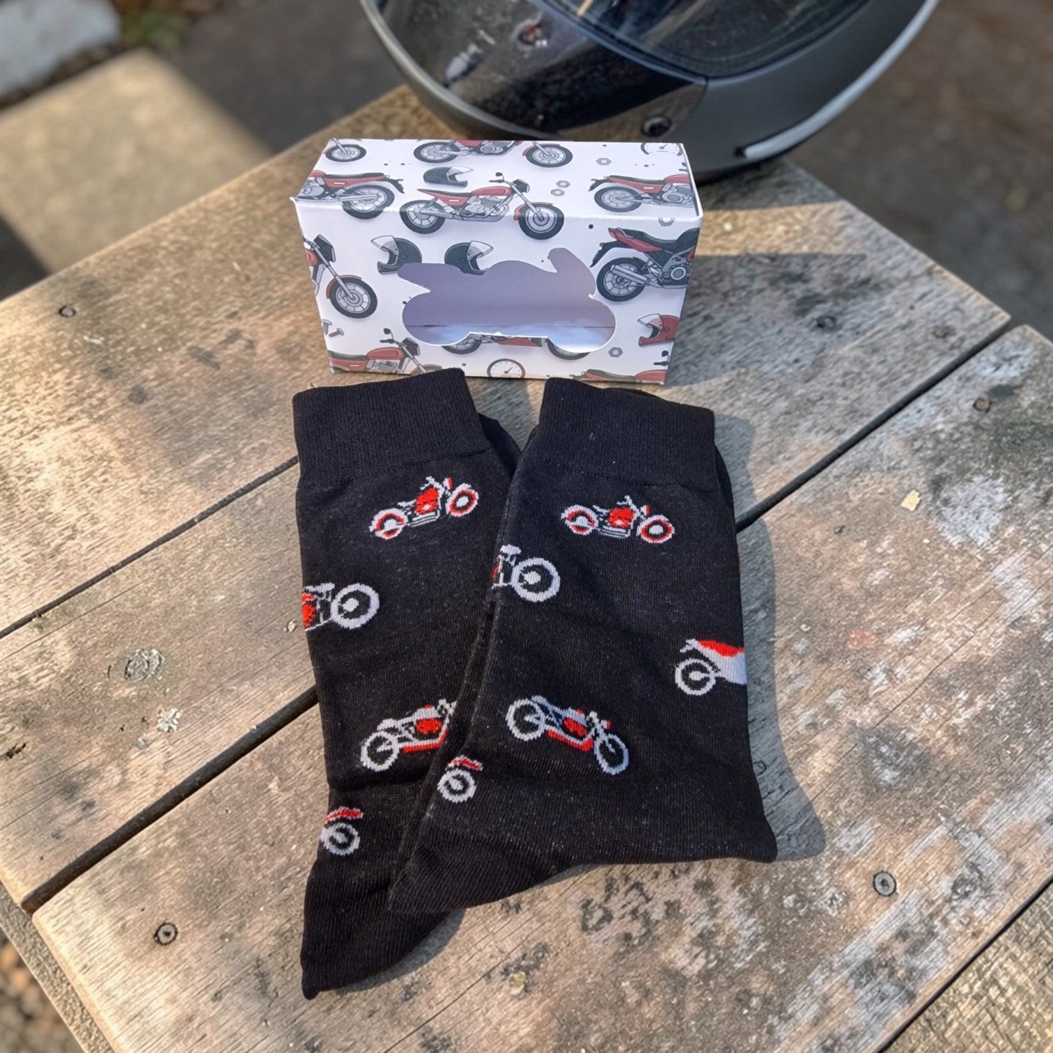 Black socks with motorcycle patterns on a wooden surface next to a patterned box.