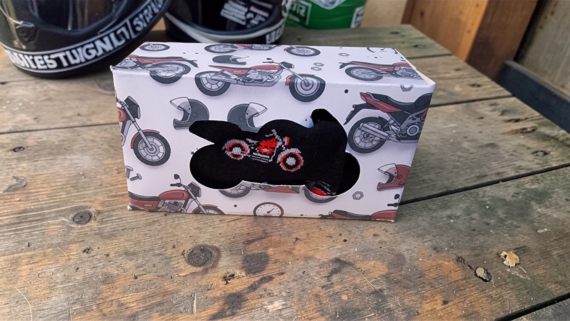Box with motorcycle design and black plush toy on a wooden surface